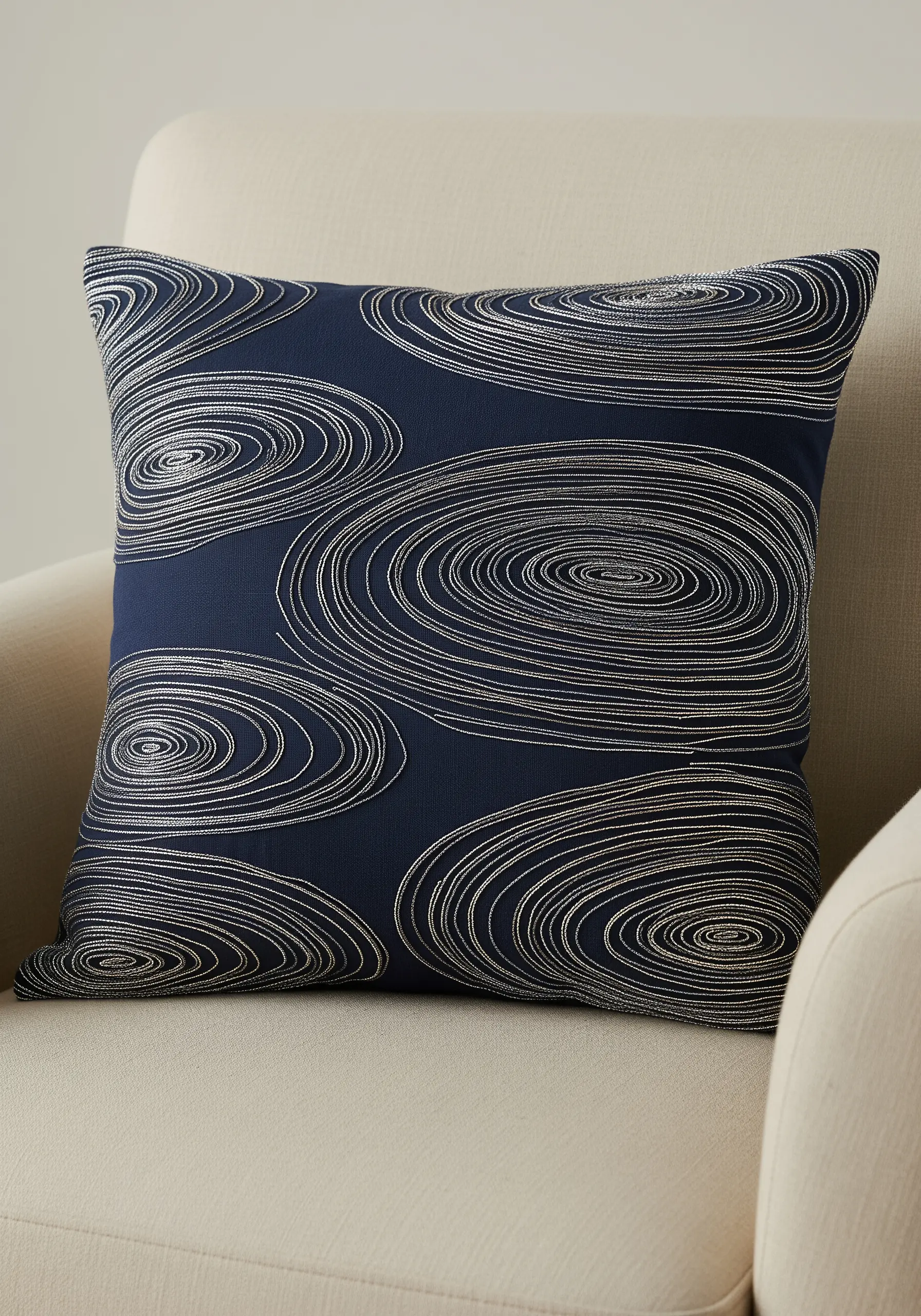 Navy blue cushion embroidered with concentric silver circles resembling water ripples.