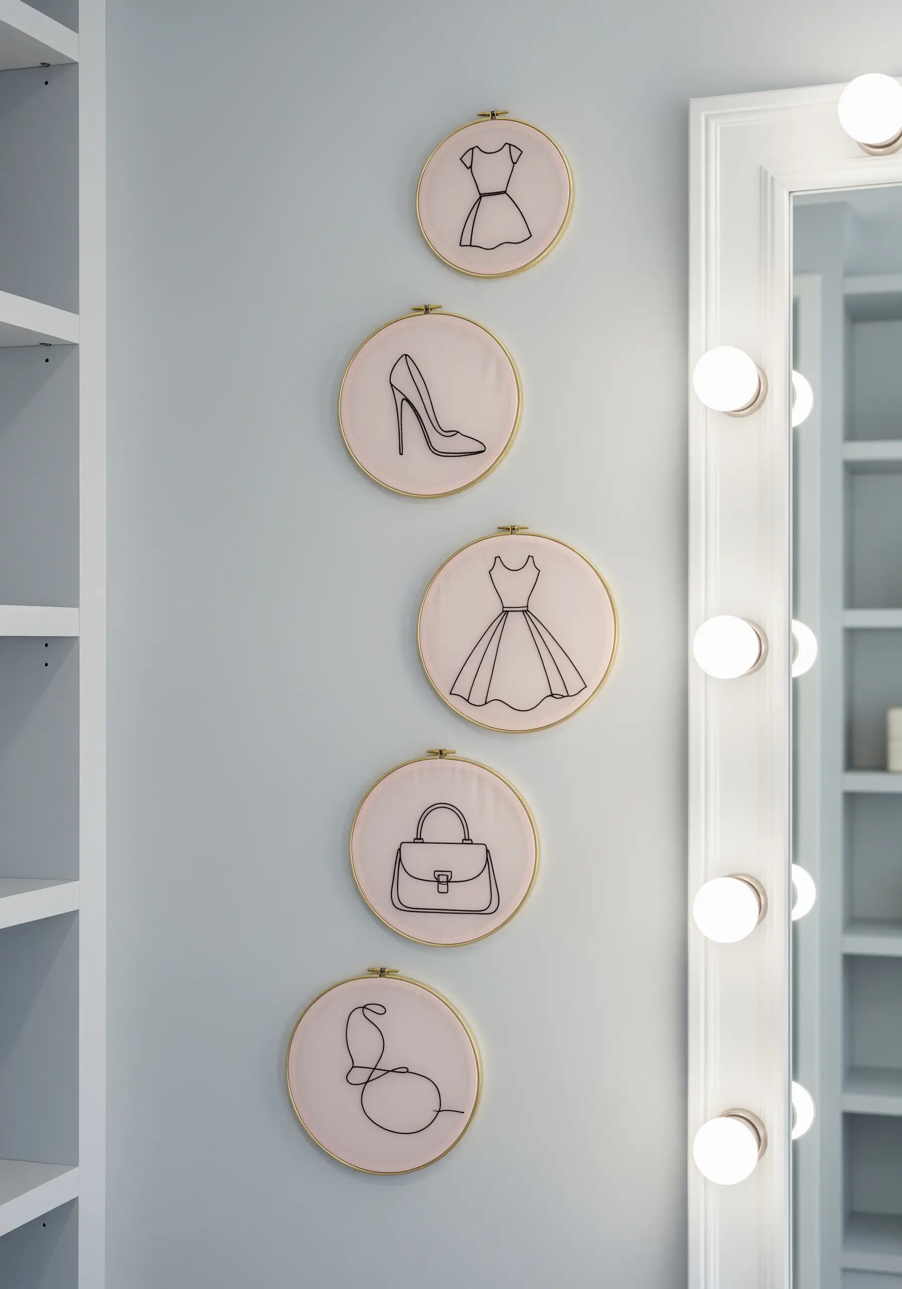 A vertical arrangement of hoops with minimalist line art of fashion items on pink fabric.