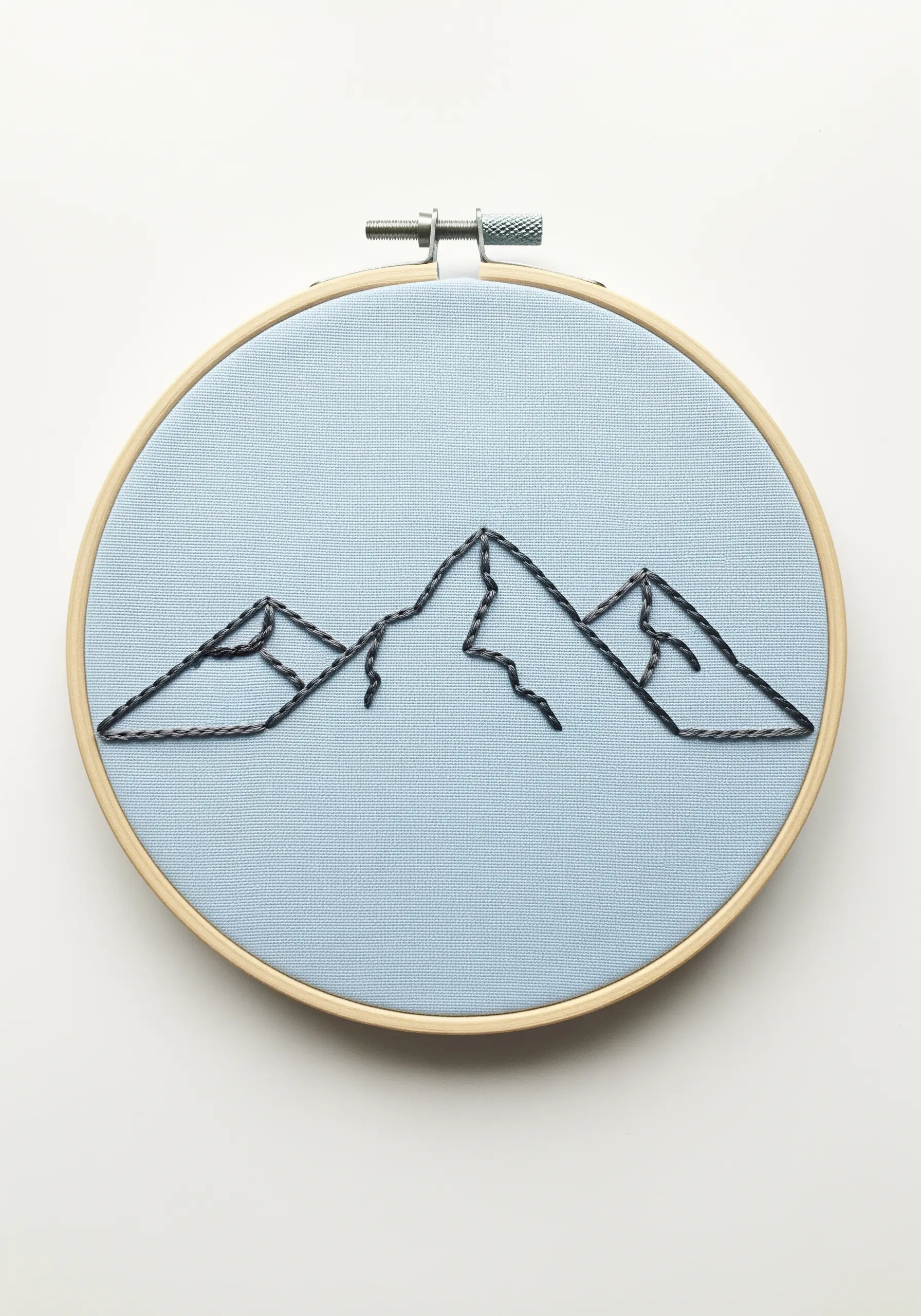 Minimalist mountain range outline embroidered with a thick, textured stitch.