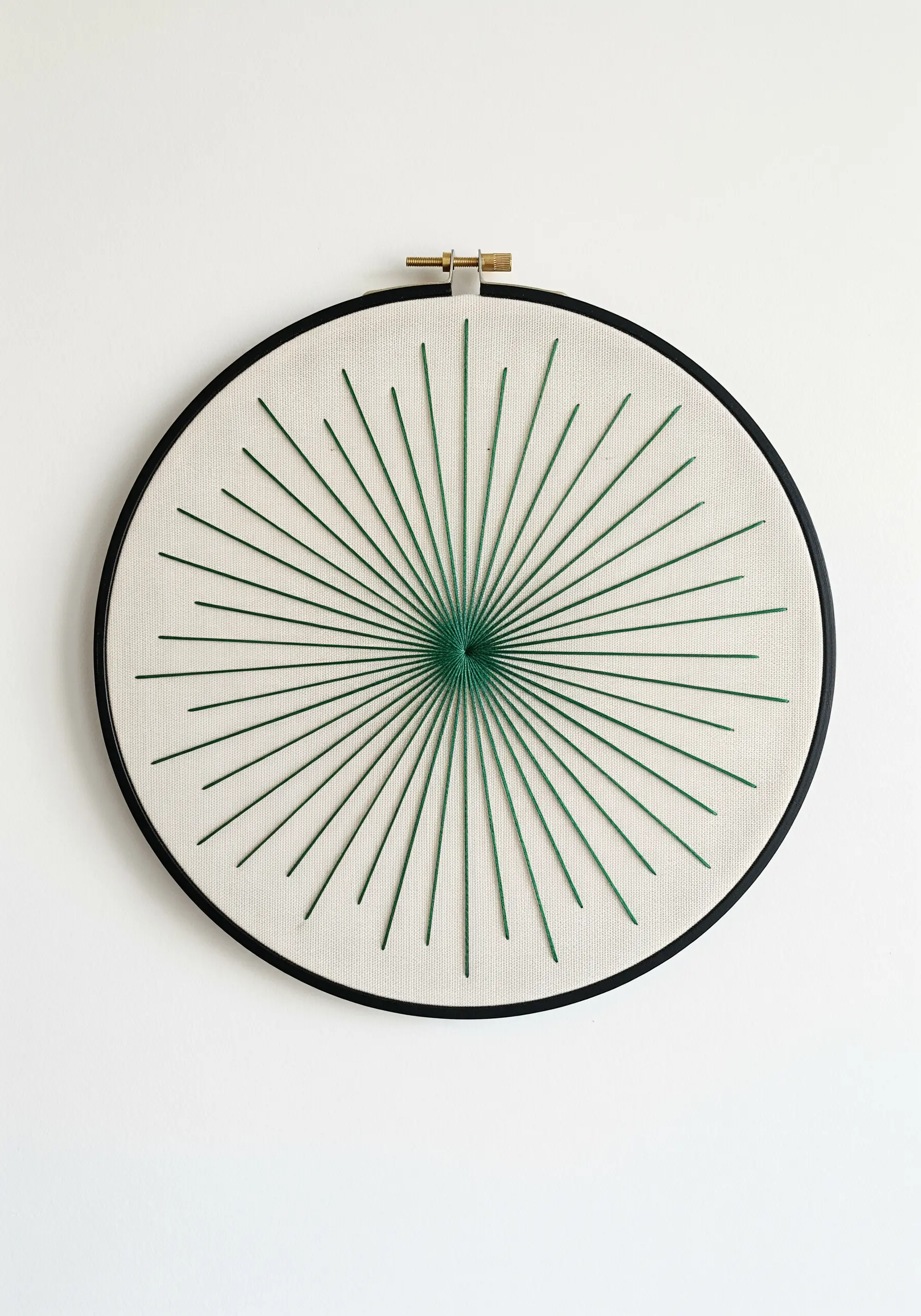 A minimalist mandala made of radiating green straight stitches in a black hoop.