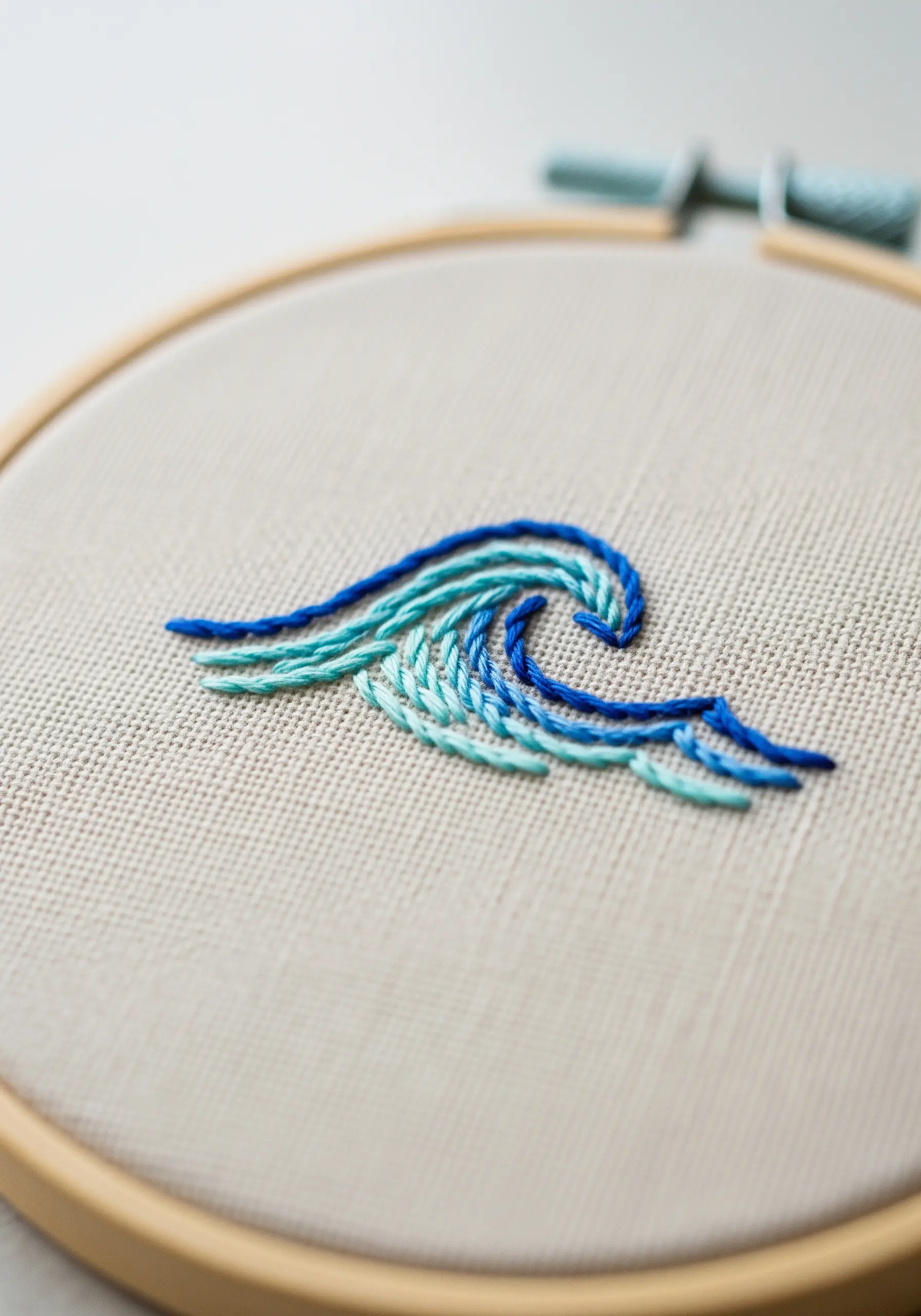 Minimalist embroidered wave using four shades of blue in parallel lines.