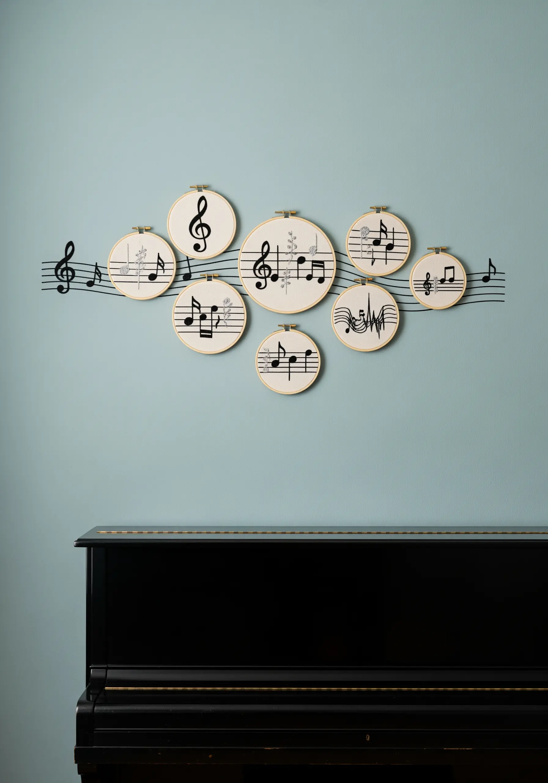 A series of embroidered musical notes in hoops, connected by a staff line on the wall.