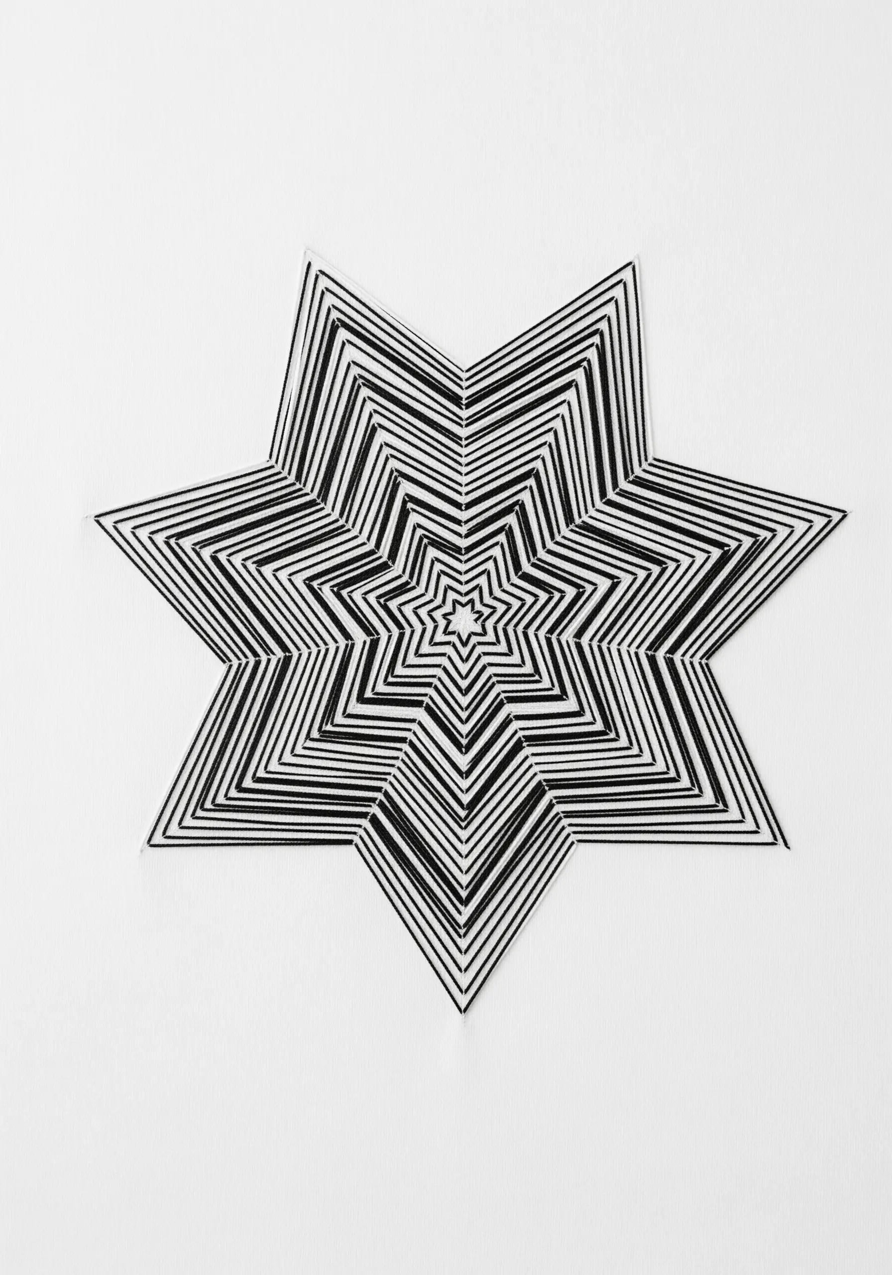 A black and white star embroidery creating an optical illusion with chevron patterns.