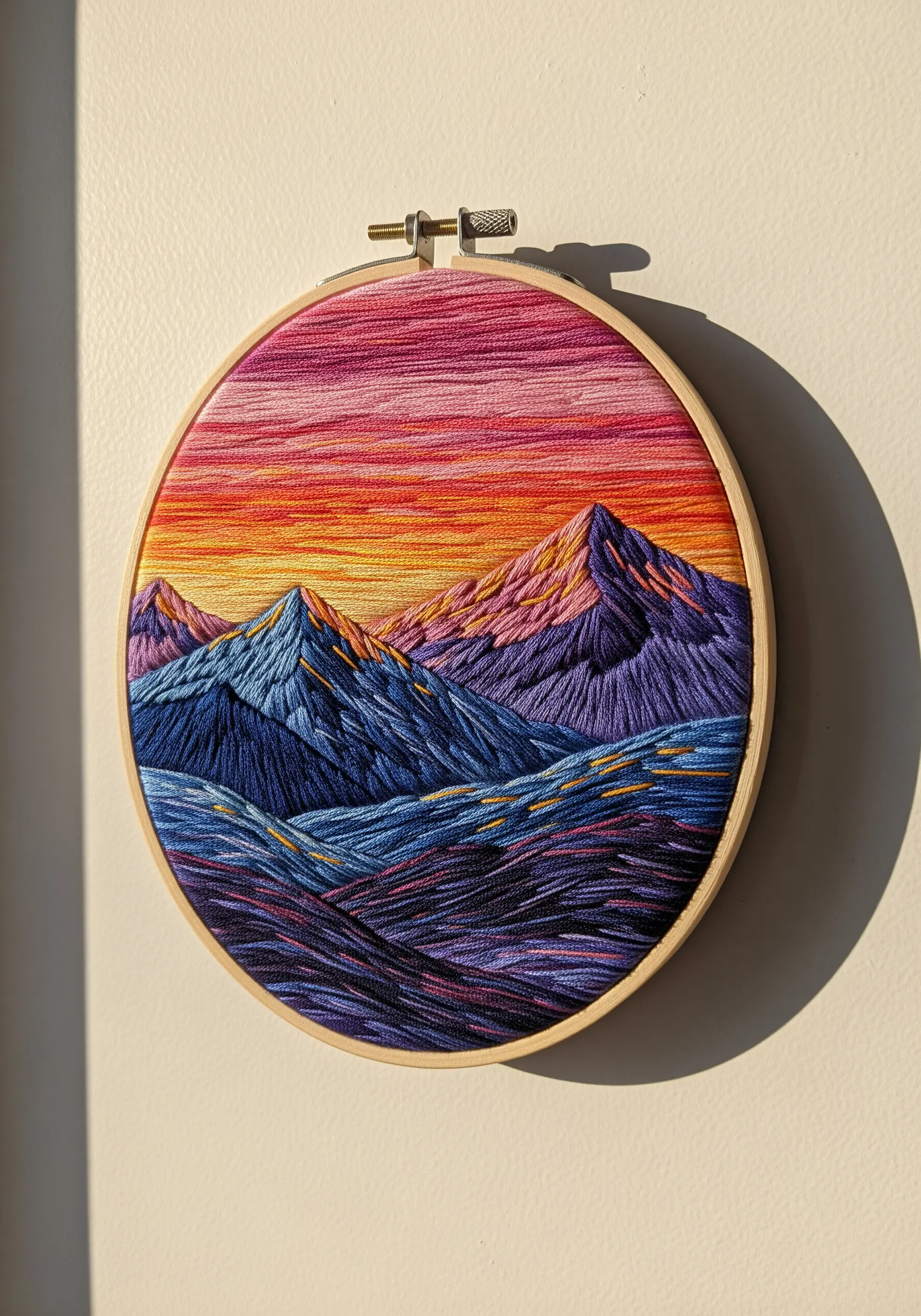Embroidered mountain landscape at sunset with vibrant thread painting.