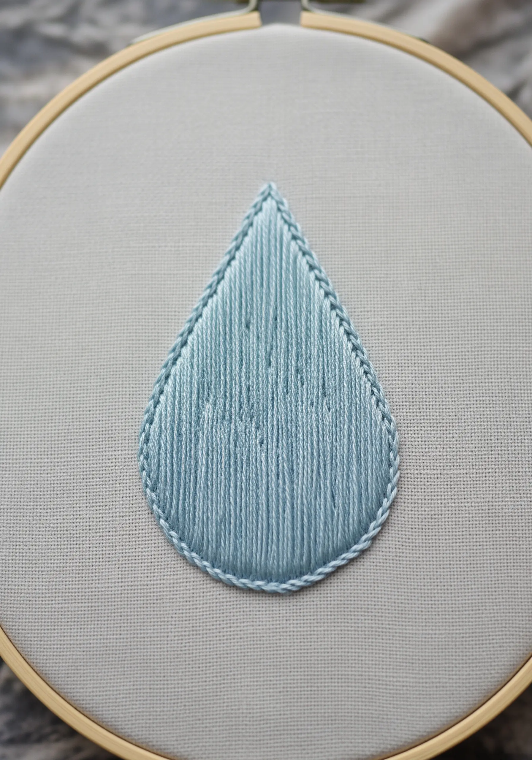 A perfectly filled teardrop shape in light blue satin stitch with a neat outline.