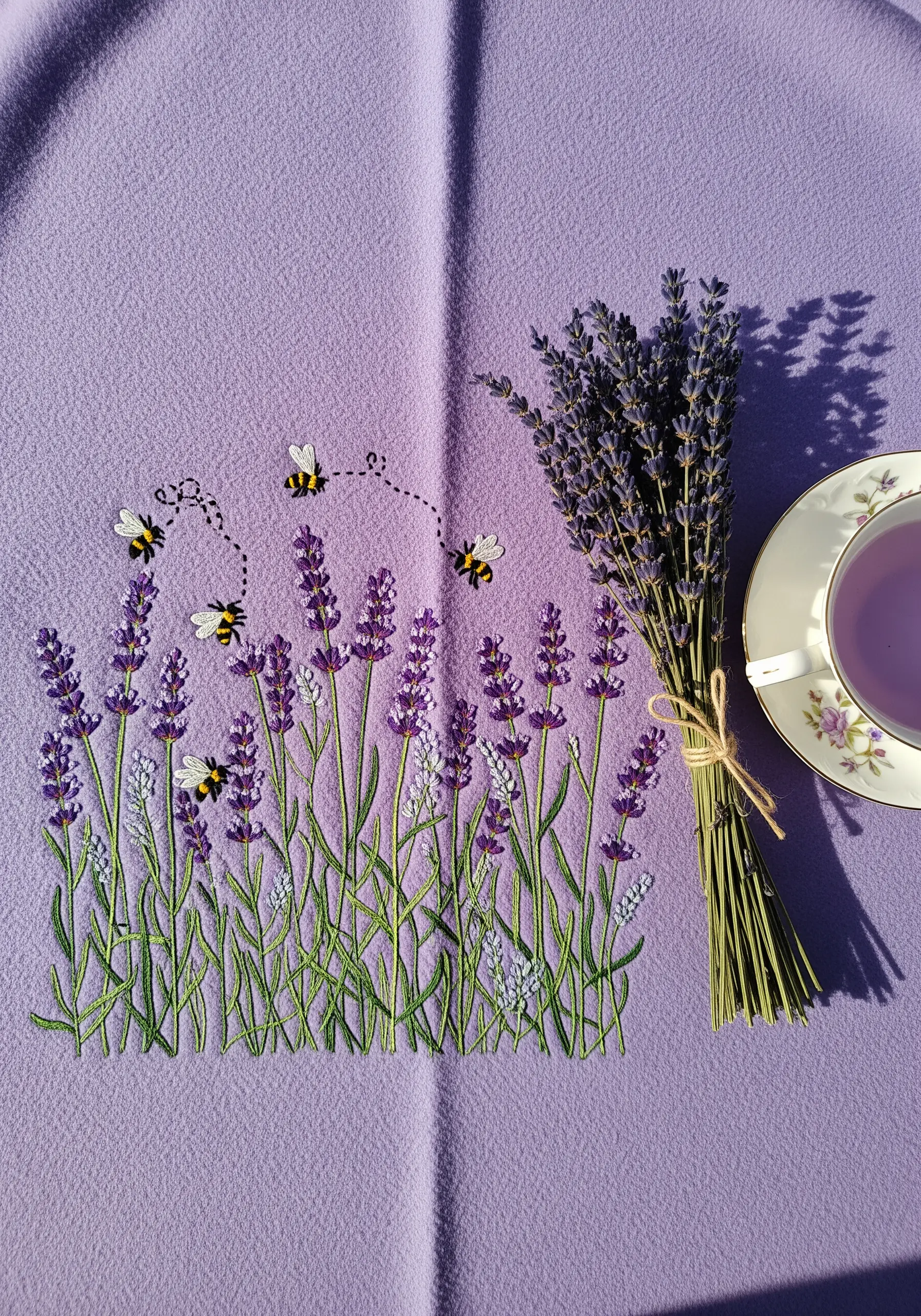 A field of embroidered lavender with small bumblebees on a purple fleece blanket.