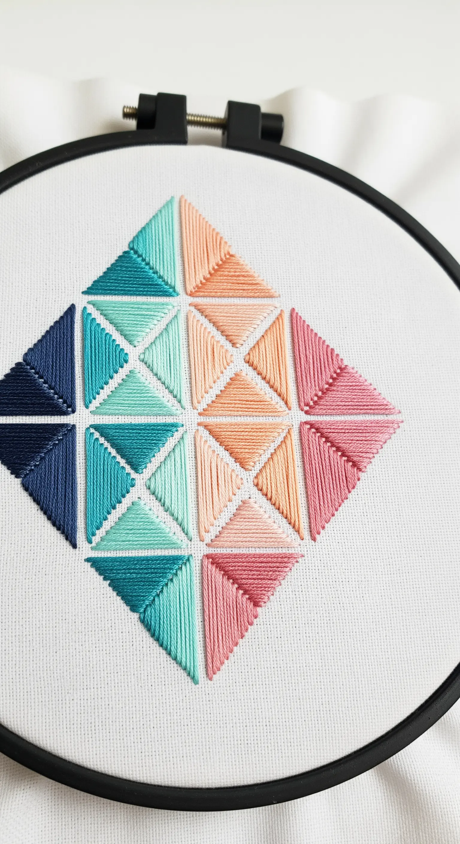 Geometric diamond pattern filled with precisely angled satin stitches in pastel hues.