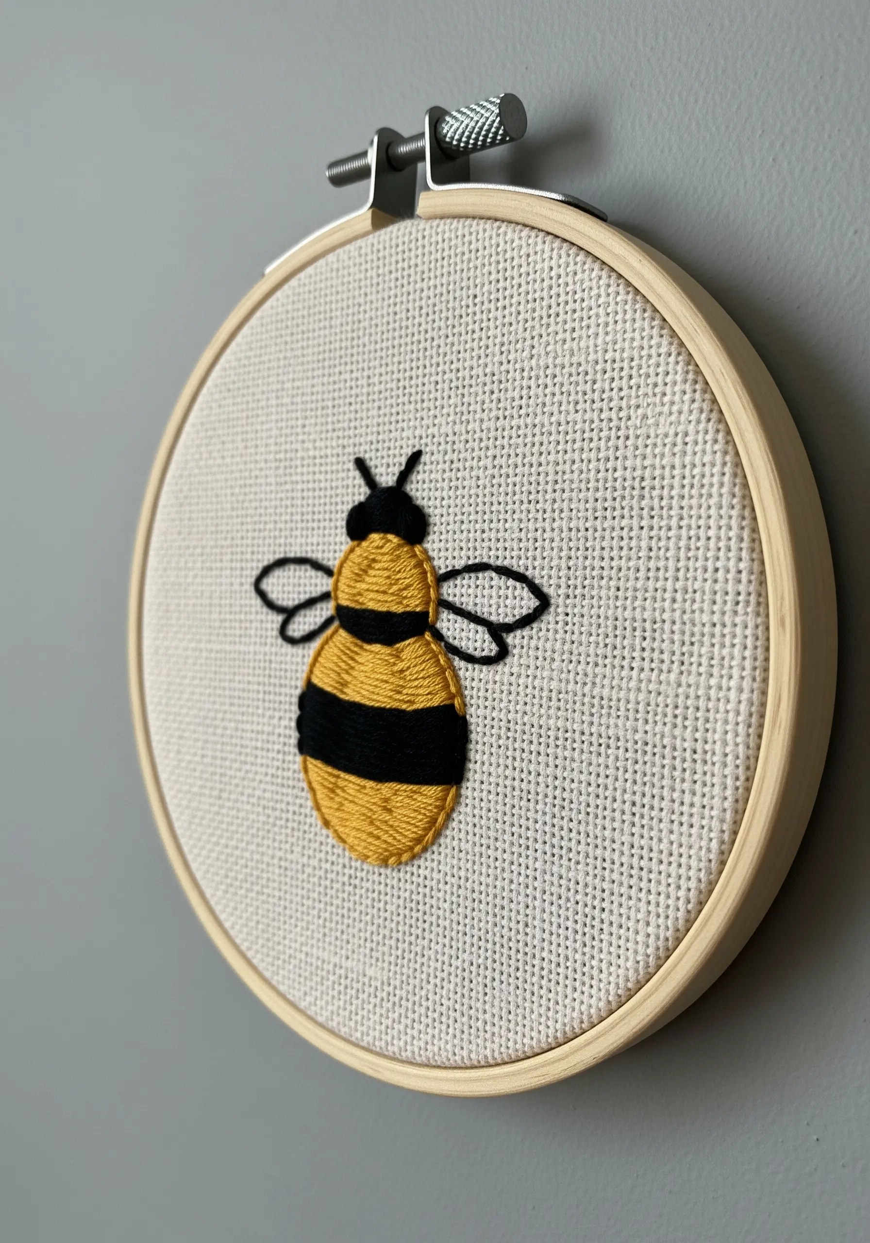 Embroidered bee with yellow and black satin-stitched stripes and delicate wings.