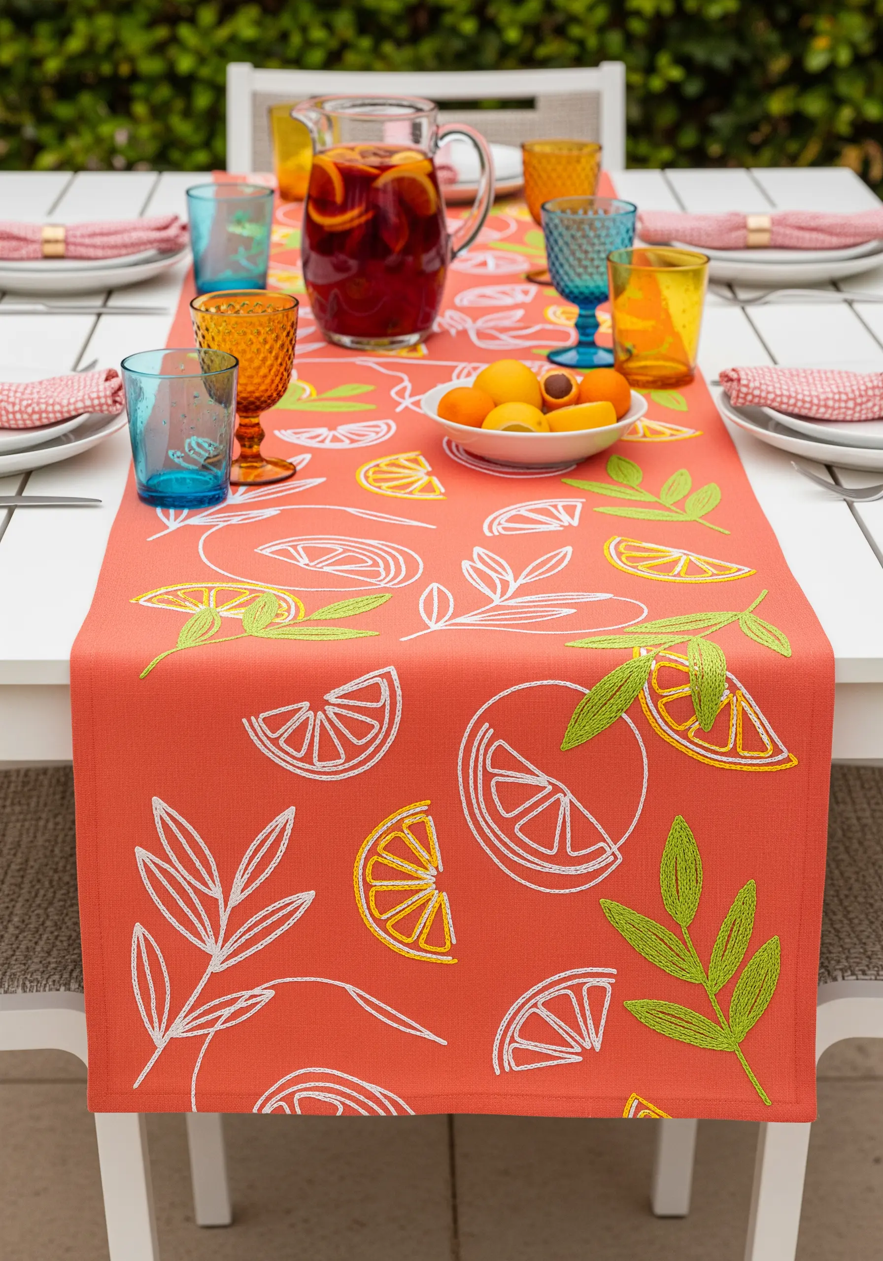 Graphic citrus slices and leaves embroidered with open seed stitch fills on a coral runner.