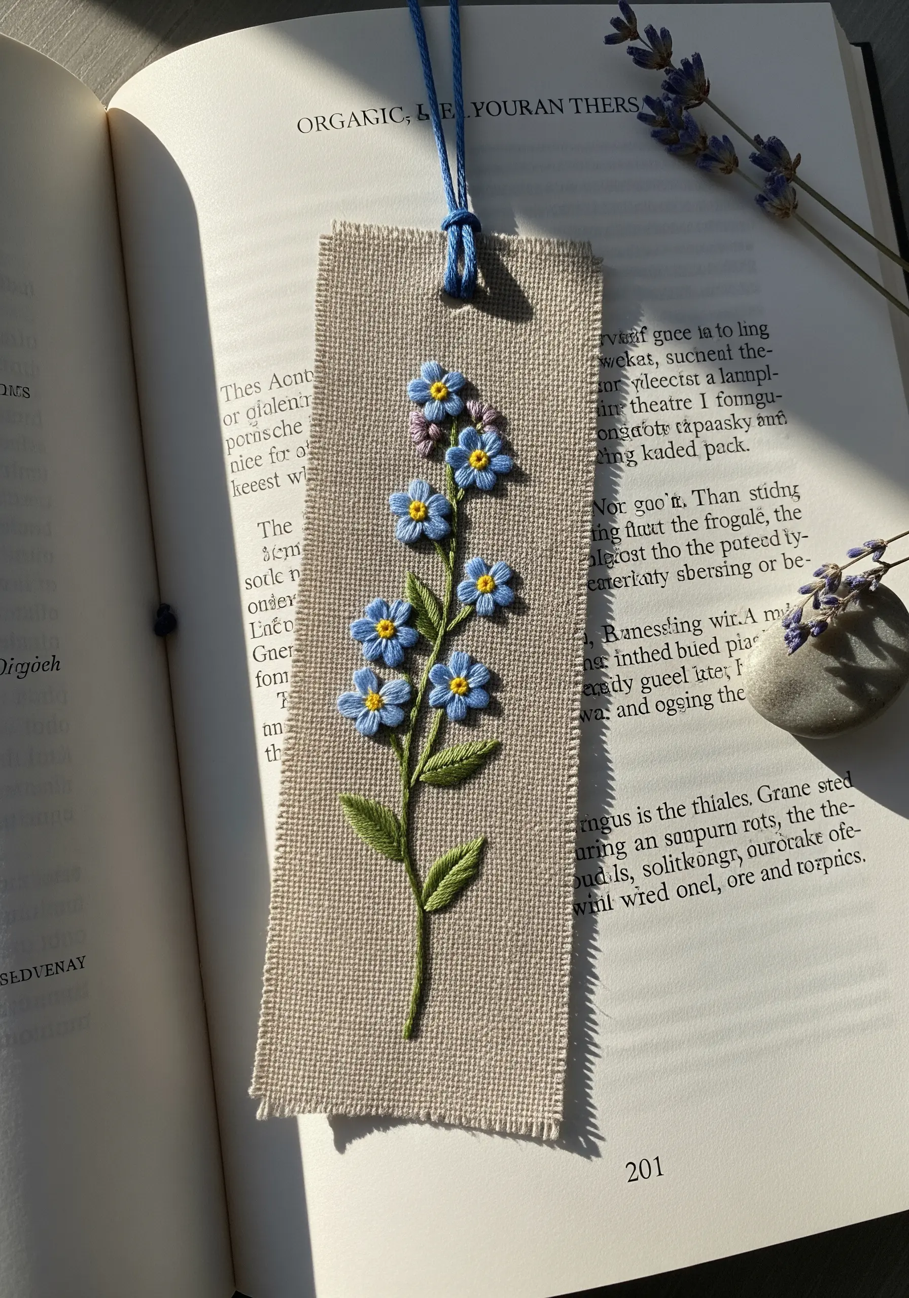 A small floral embroidery of forget-me-nots stitched on a scrap of linen for a bookmark.