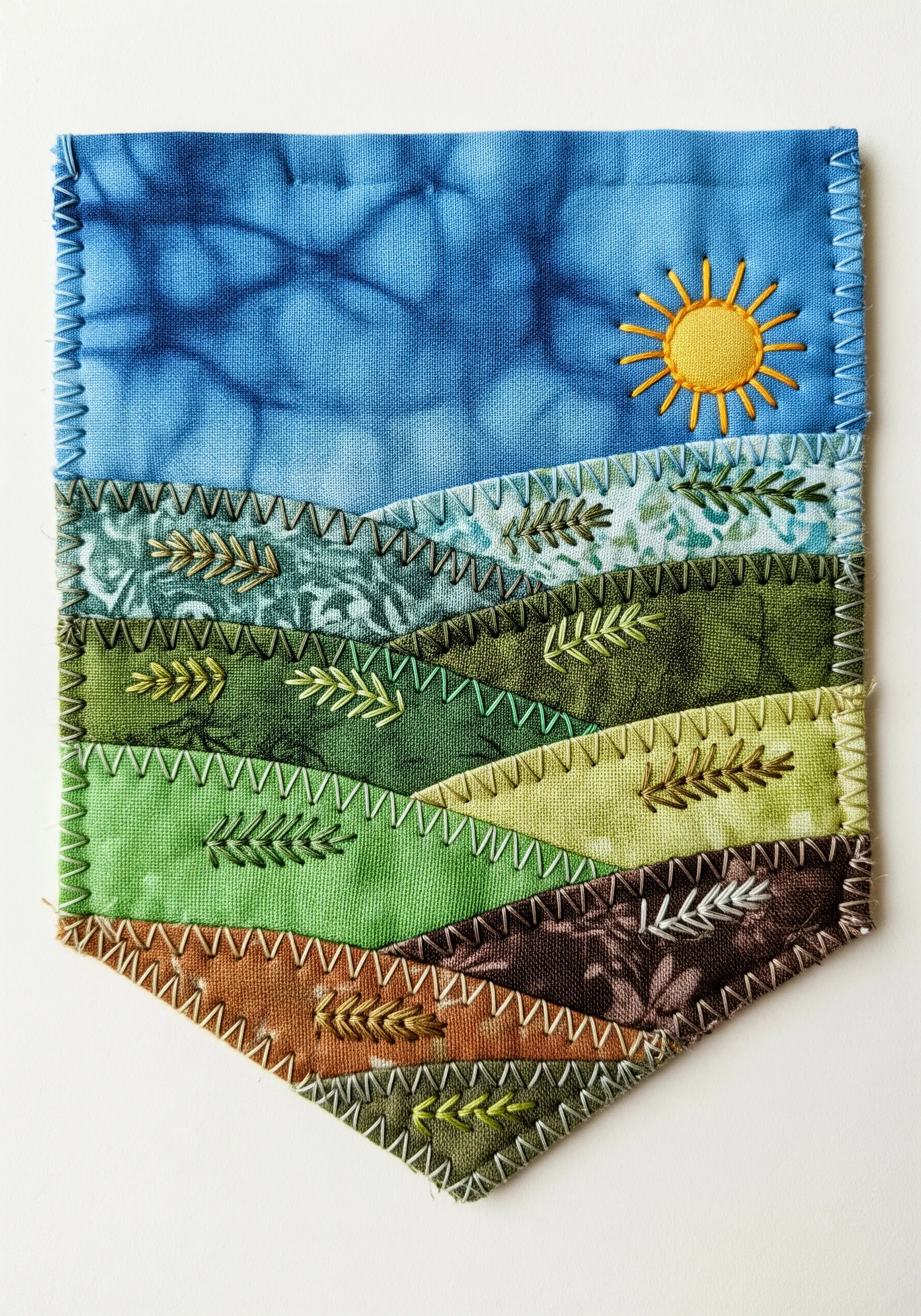 Fabric collage landscape banner made from green and blue fabric scraps with decorative stitching.