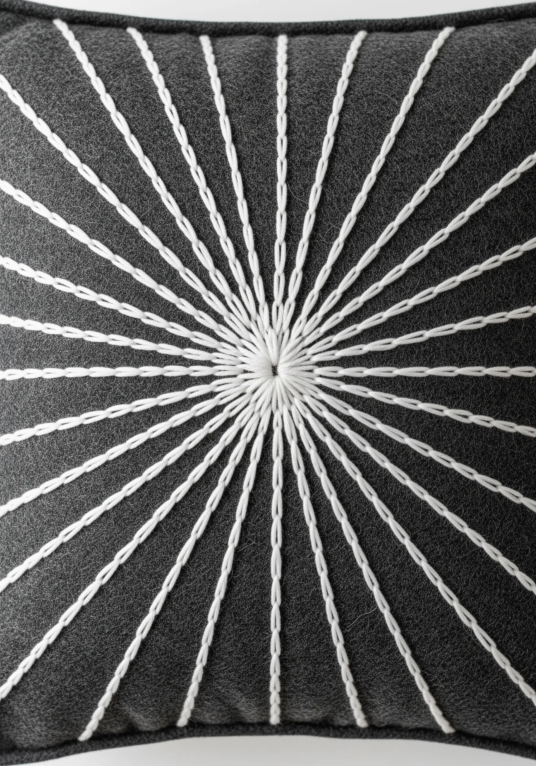 White threads radiating from a central point on a dark grey wool cushion.
