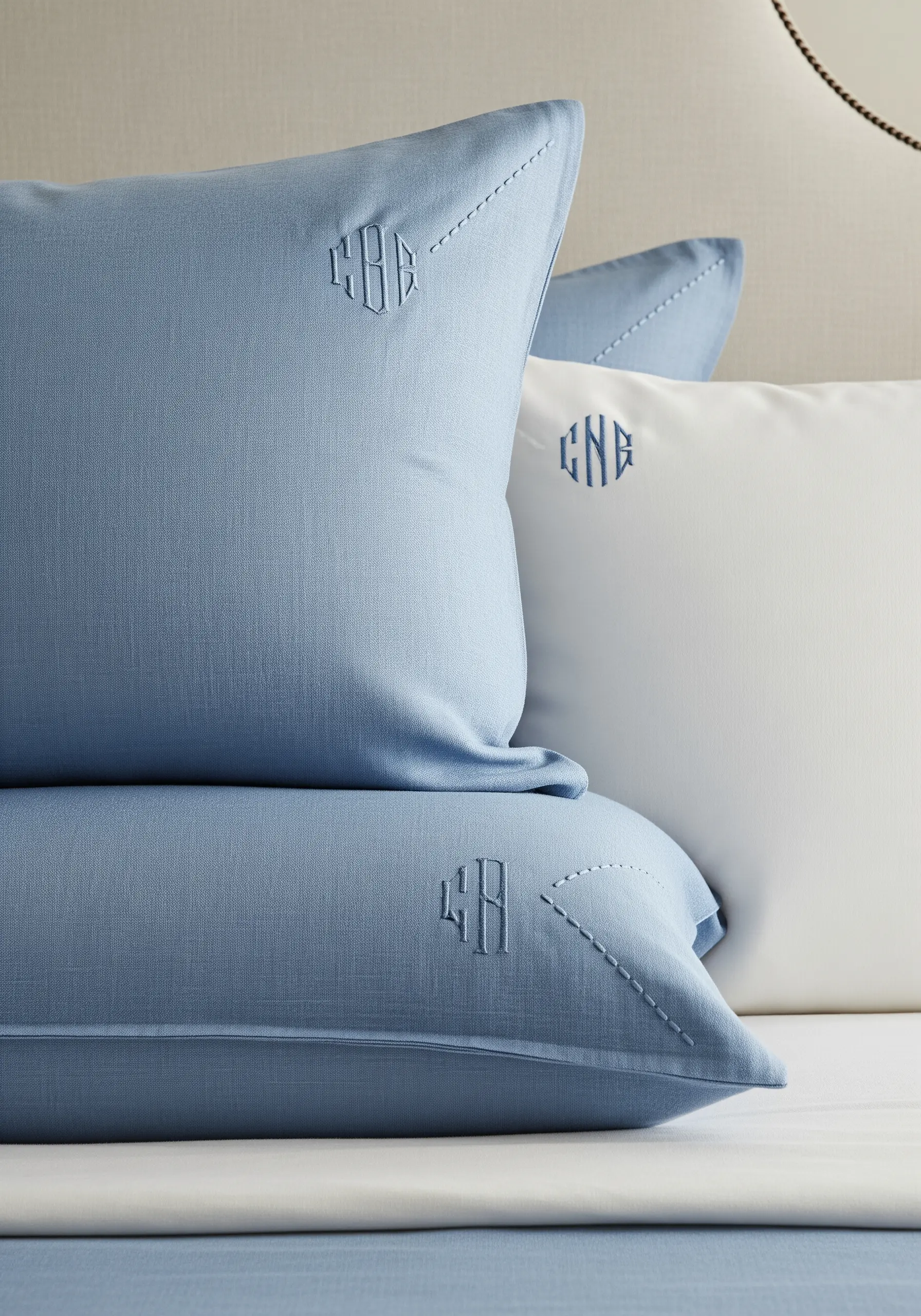 Blue and white pillows with elegant, tone-on-tone embroidered monograms and corner stitch details.