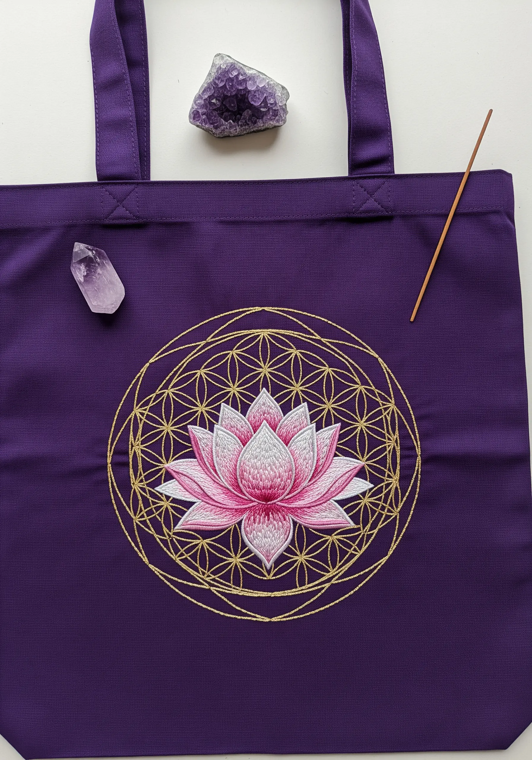 A pink and white lotus embroidered over a gold metallic Flower of Life pattern on a purple tote.