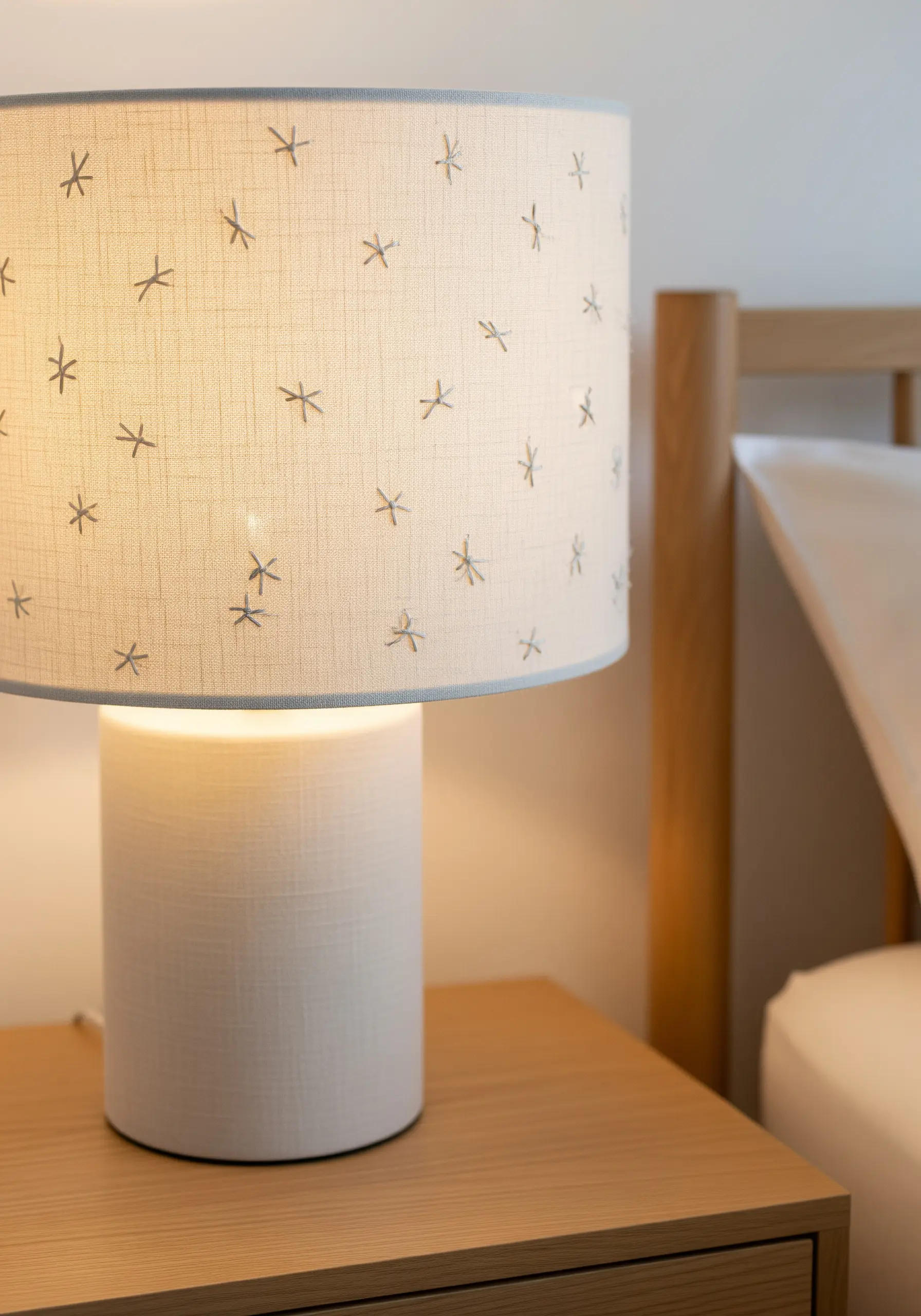 Simple grey starburst stitches scattered across a linen drum lampshade.