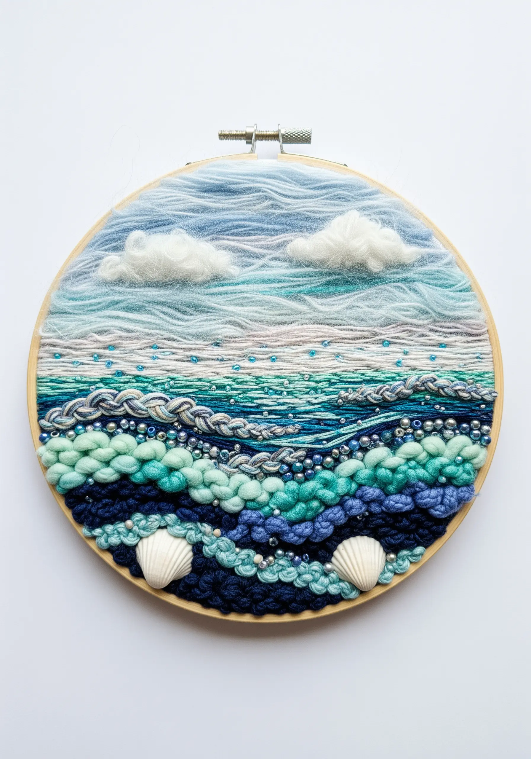 Hoop art seascape with textured yarn waves, beads, felted clouds, and real shells.