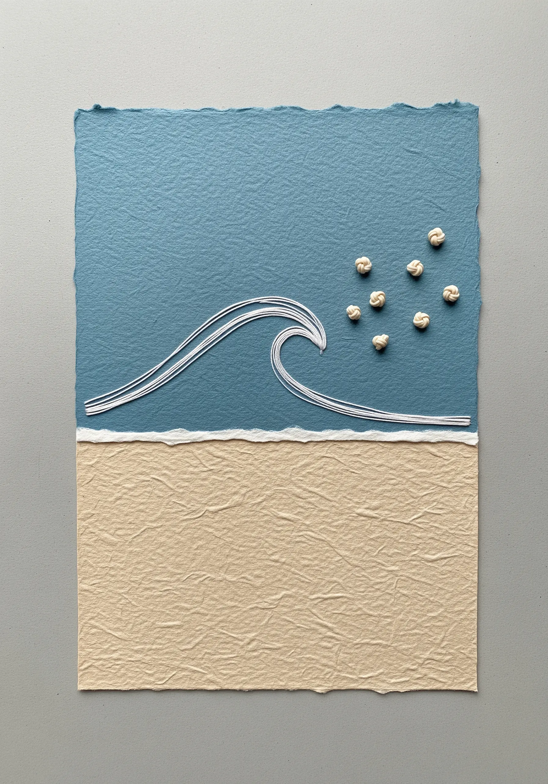 A minimalist wave stitched in white thread on blue paper, with white knots for seafoam.