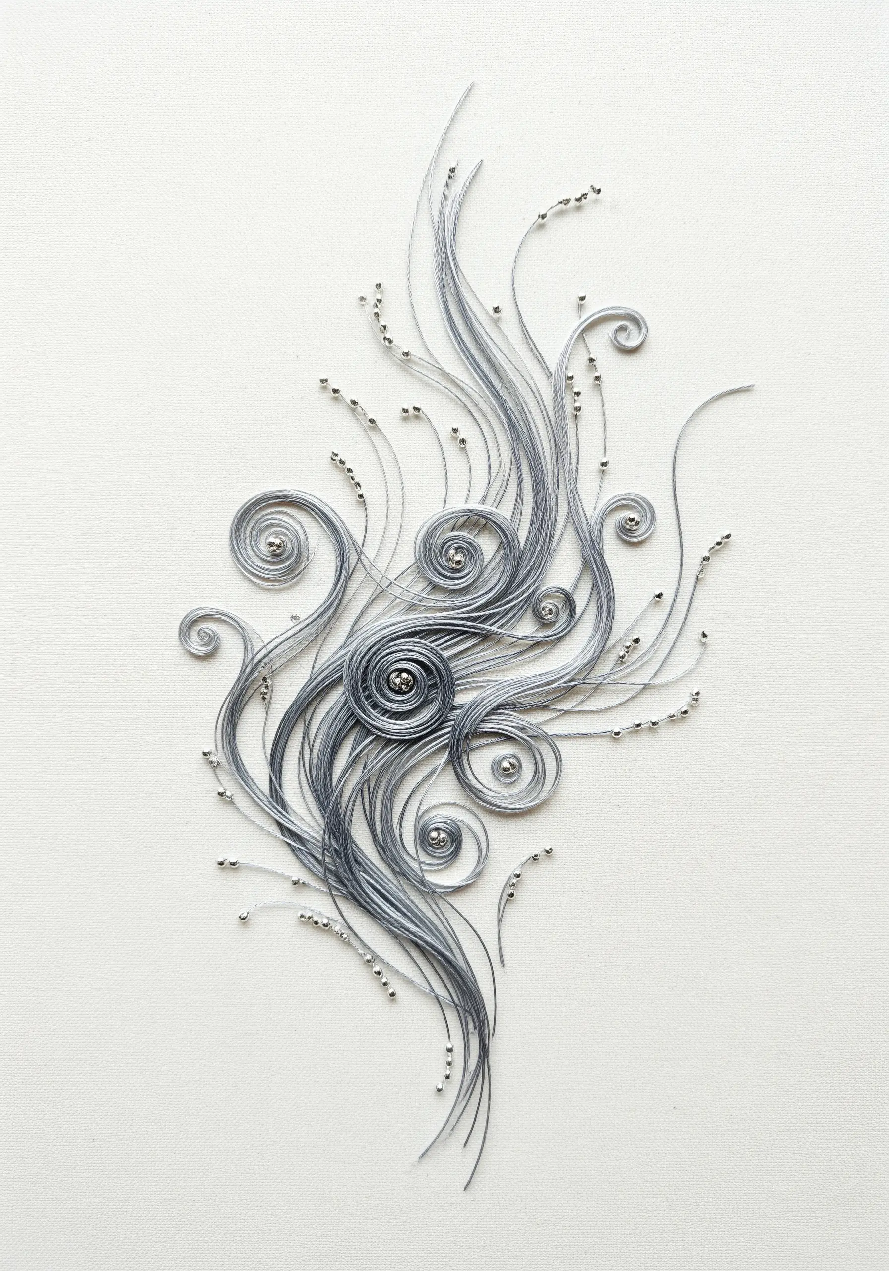 Elegant swirls of gray couched thread on a white background, accented with tiny silver beads.
