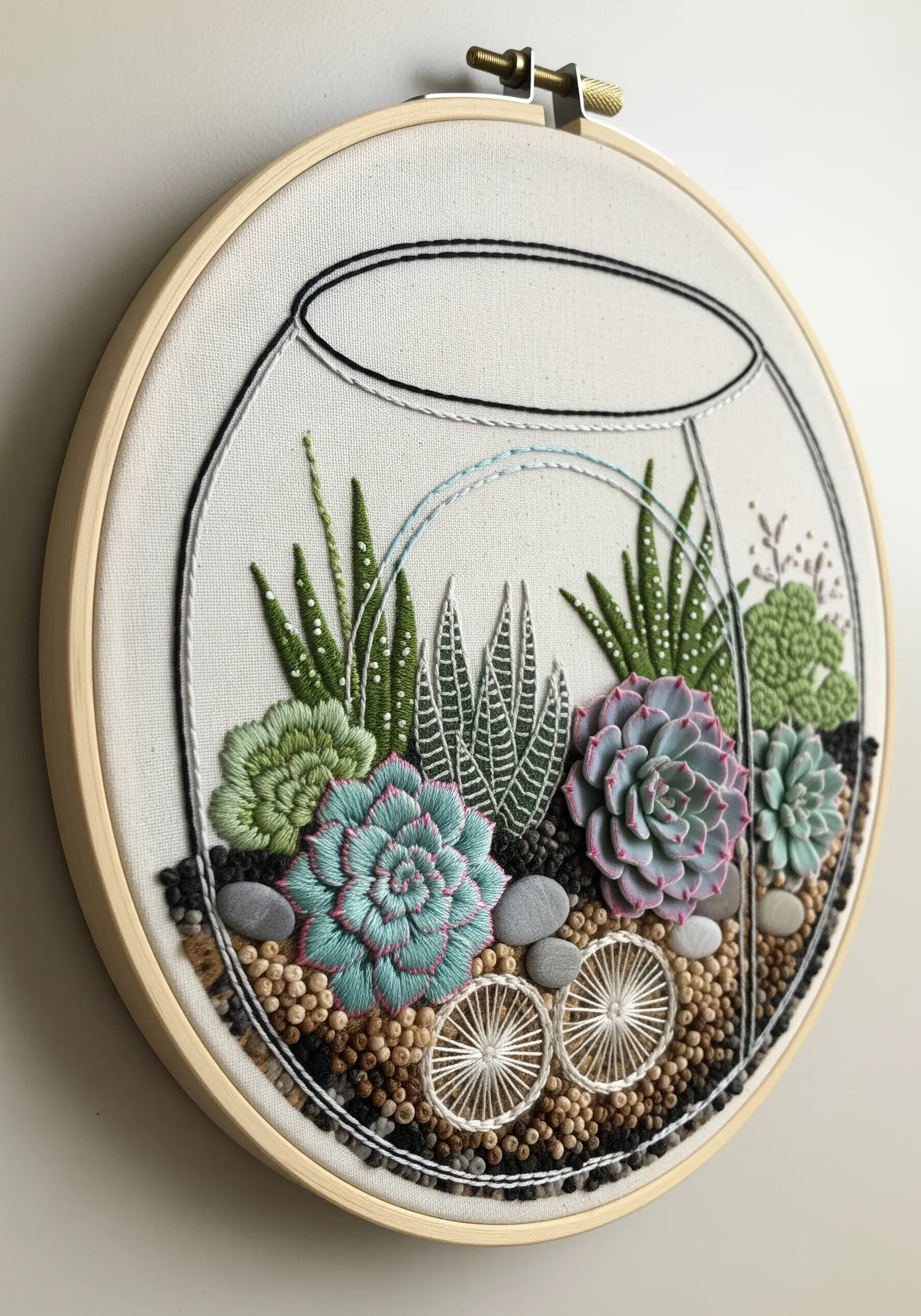 A dimensional embroidery of a succulent terrarium with textured stitches and beads.