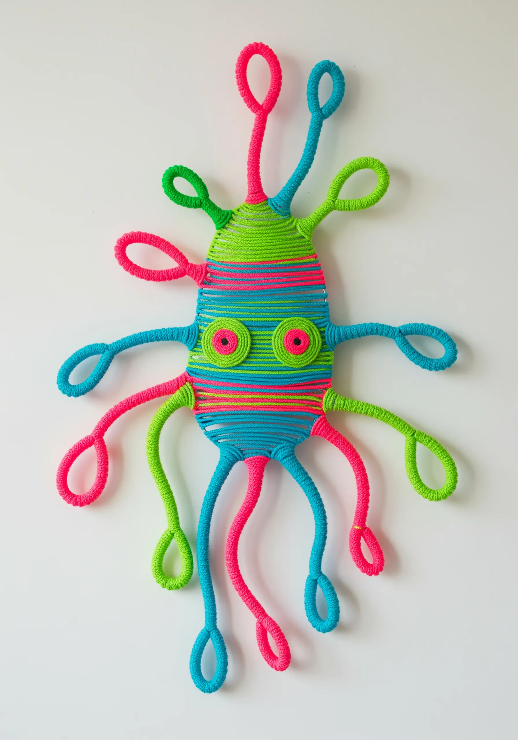 A whimsical, colorful octopus-like creature made by wrapping yarn around a wire frame.