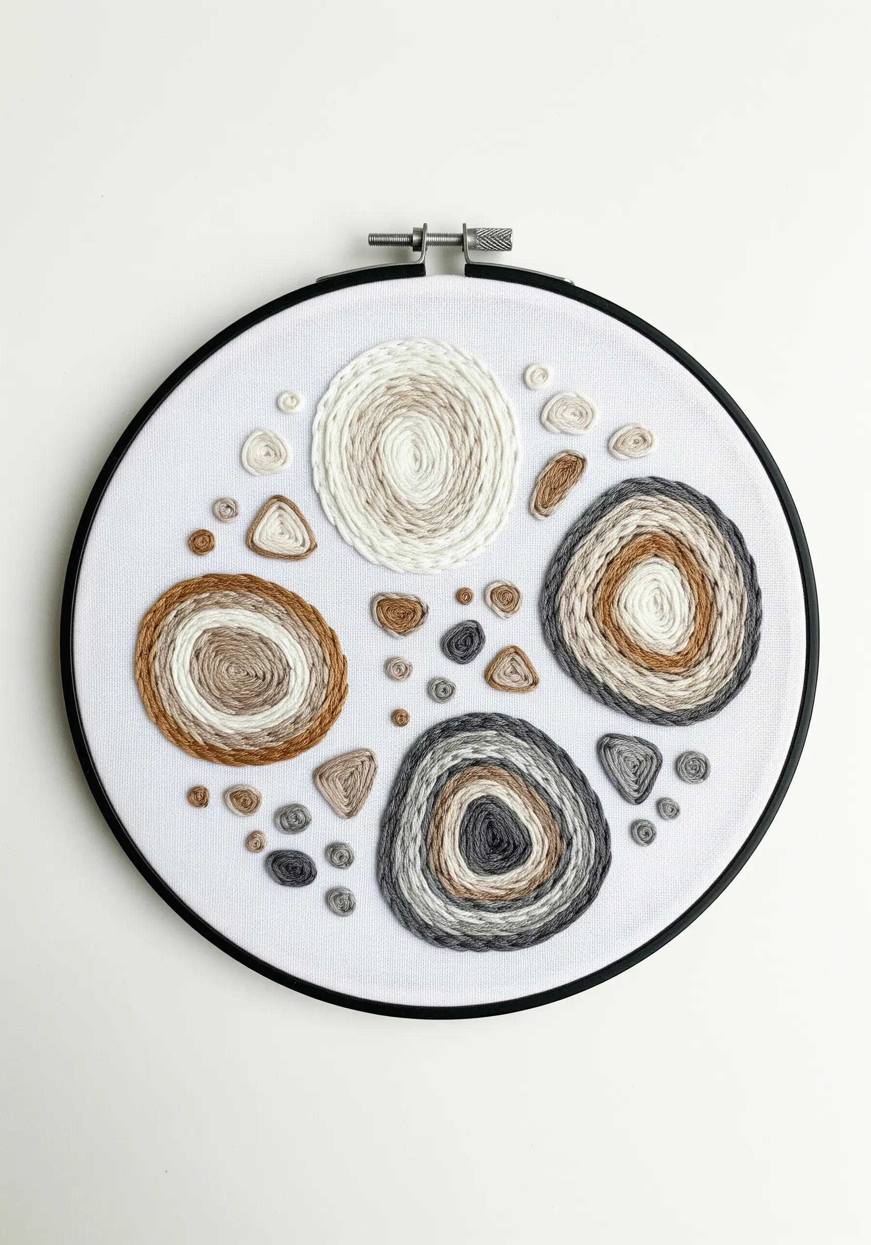 Hoop art with concentric circles of couched yarn in neutral earth tones.