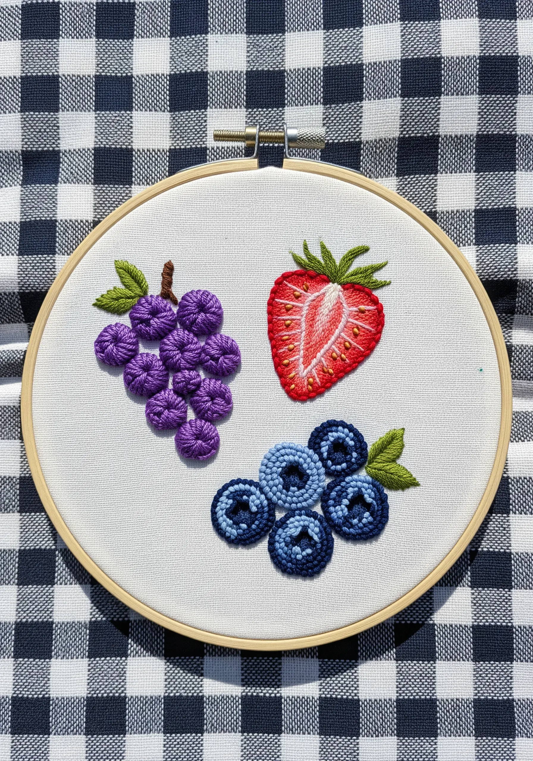 Embroidered grapes, blueberries, and a strawberry using raised knots and textural details.
