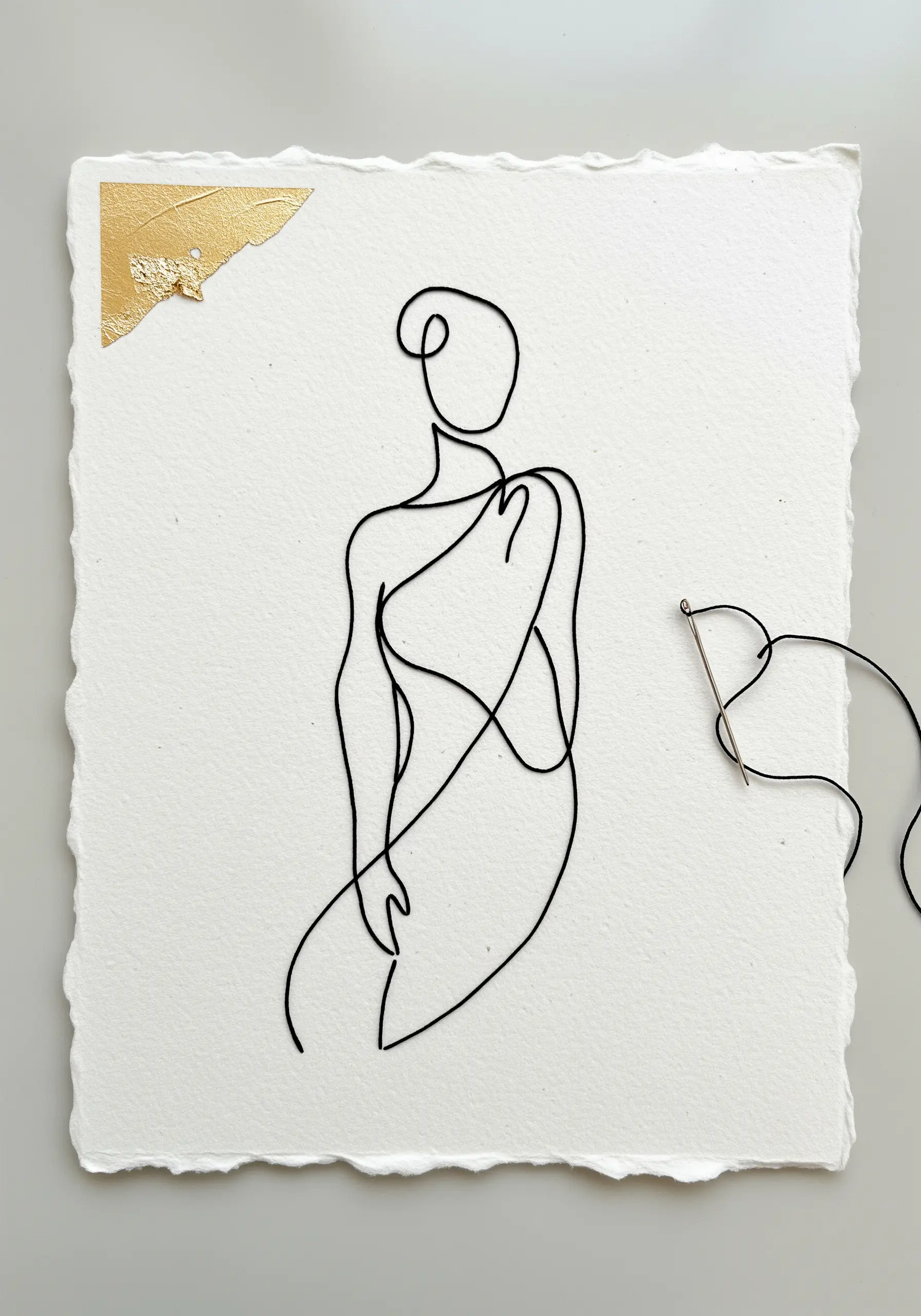 Minimalist line art figure made from black wire couched onto textured white paper with a gold leaf corner.