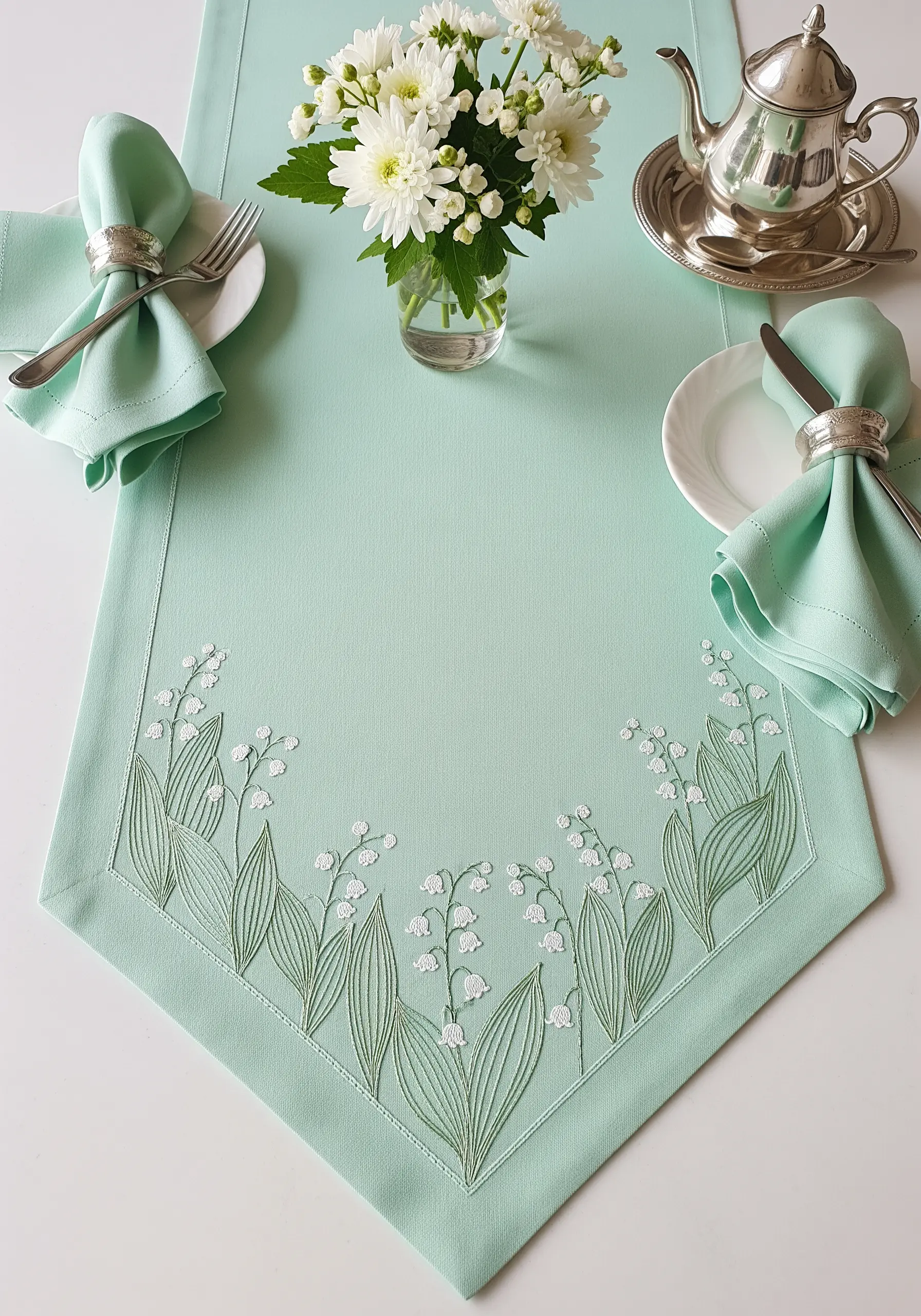 Lily of the Valley embroidered with directional satin stitch leaves on a mint green runner.