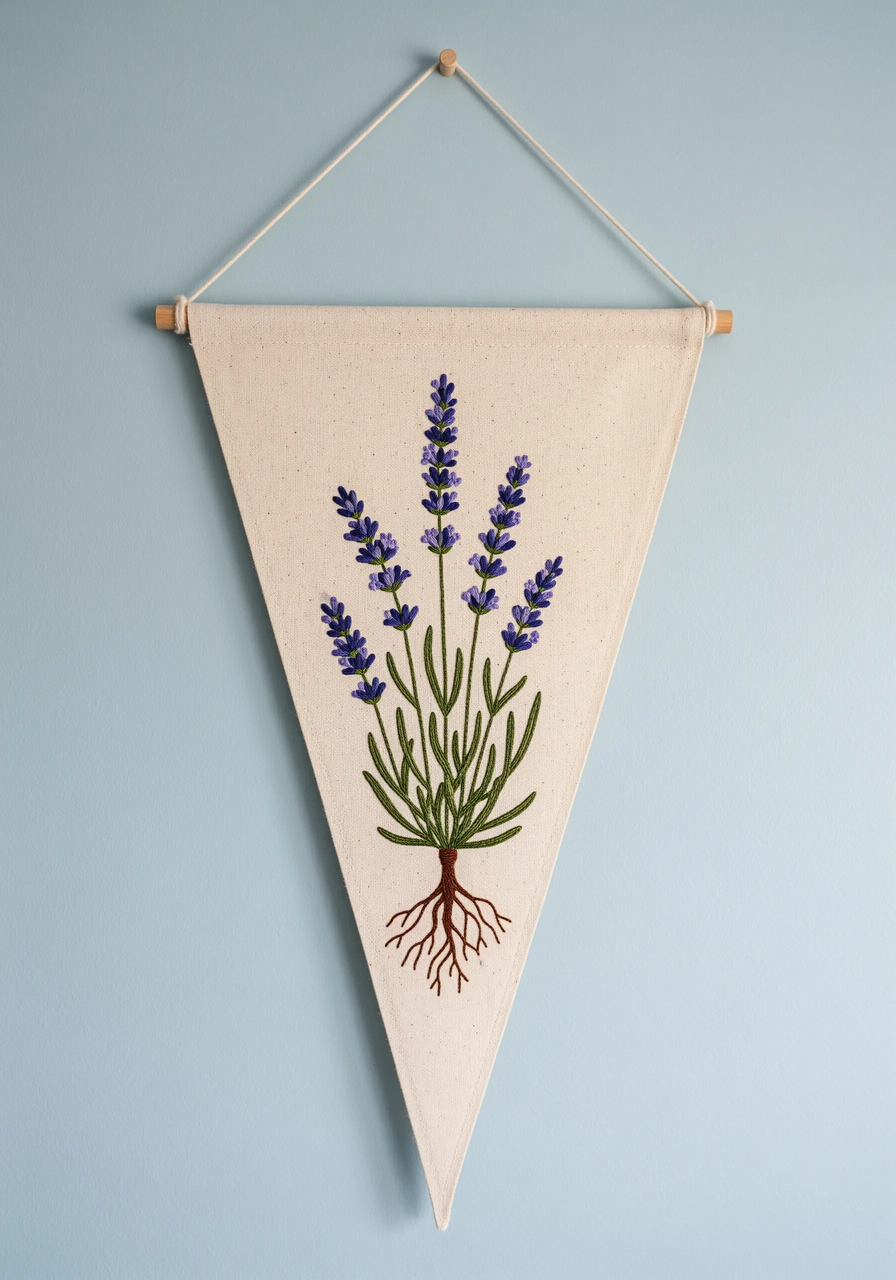 A botanical illustration-style embroidery of a lavender plant, including roots, on a canvas pennant.