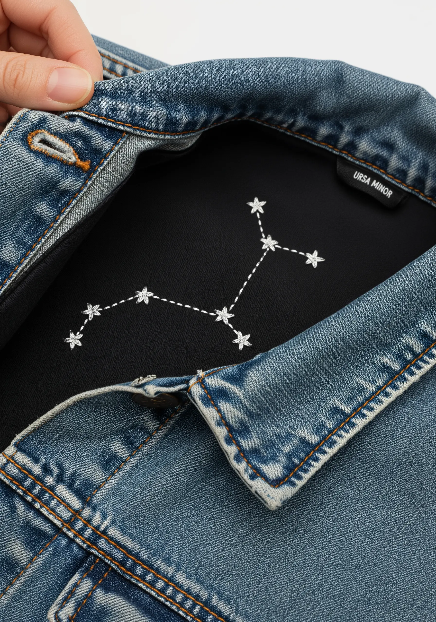 The Ursa Minor constellation embroidered in white thread on the black lining of a denim jacket collar.