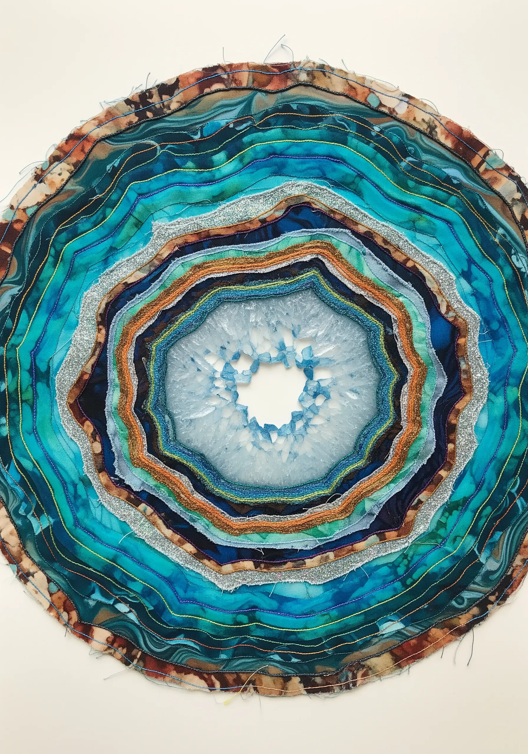 Abstract fabric art piece resembling a geode, made with layered batik and glitter fabrics.