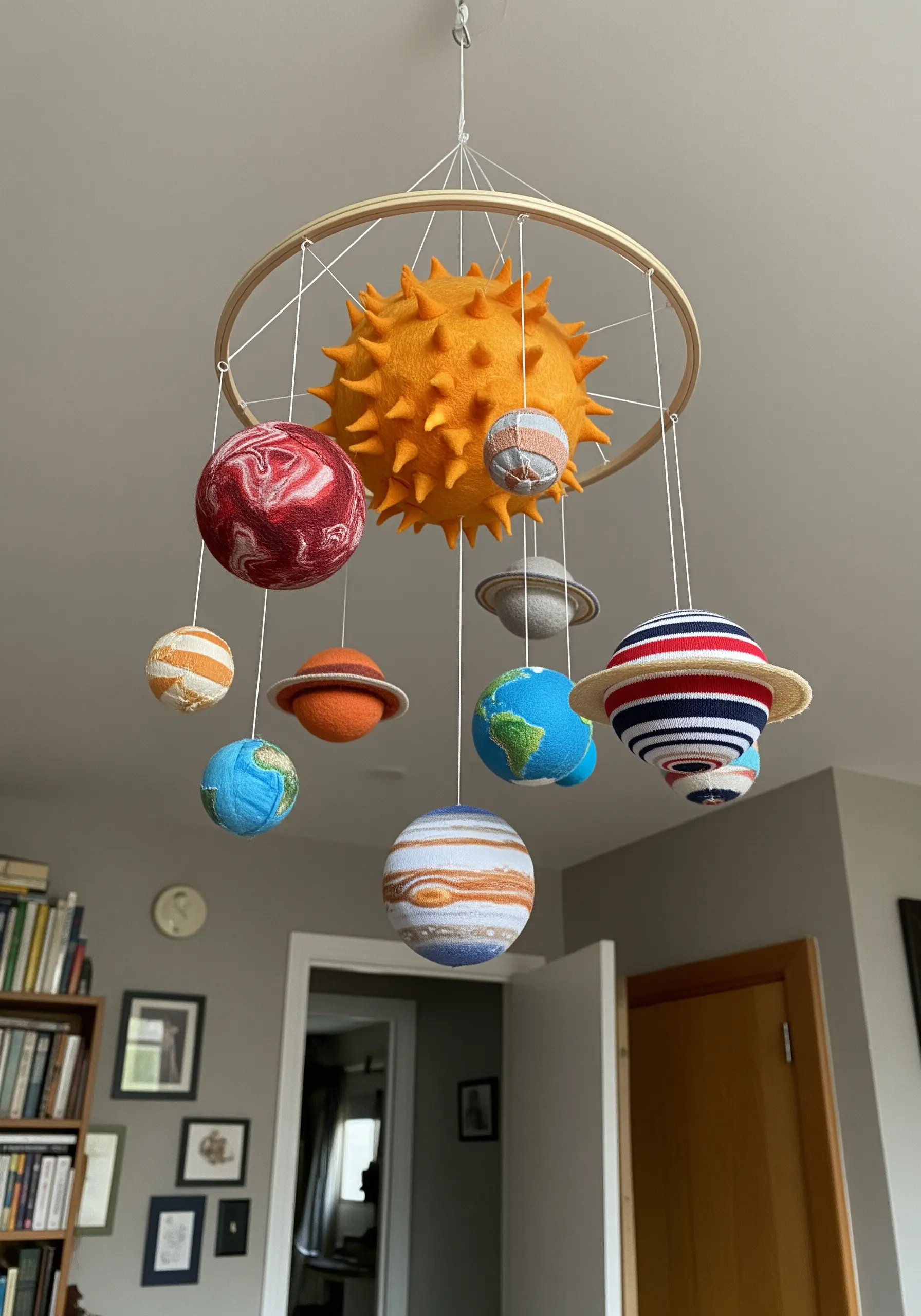 A solar system mobile with planets made from colorful, textured, upcycled sweater fabric.