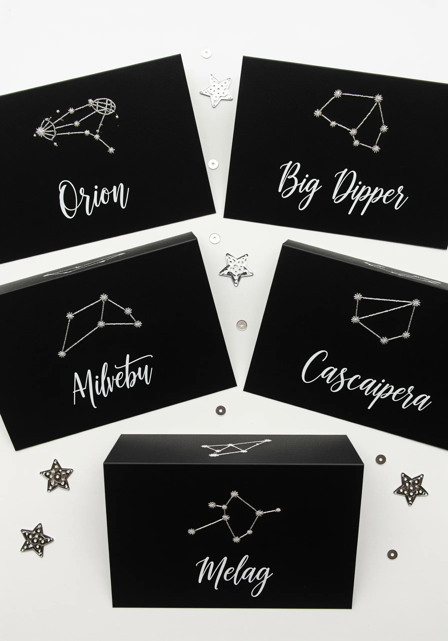 A set of black cards with various constellations stitched in white or silver thread.