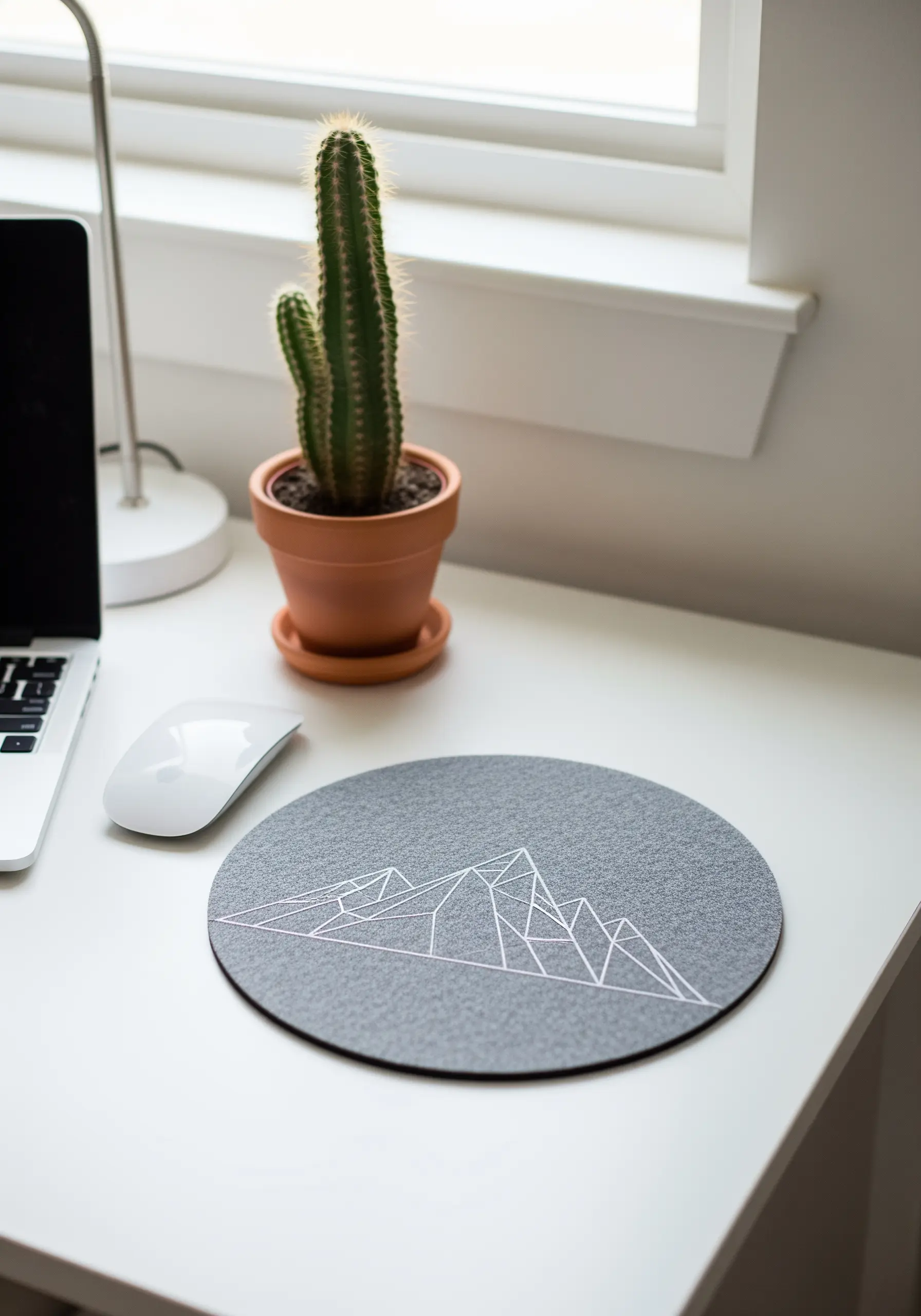 Geometric mountain range line art stitched in white on a grey felt mousepad