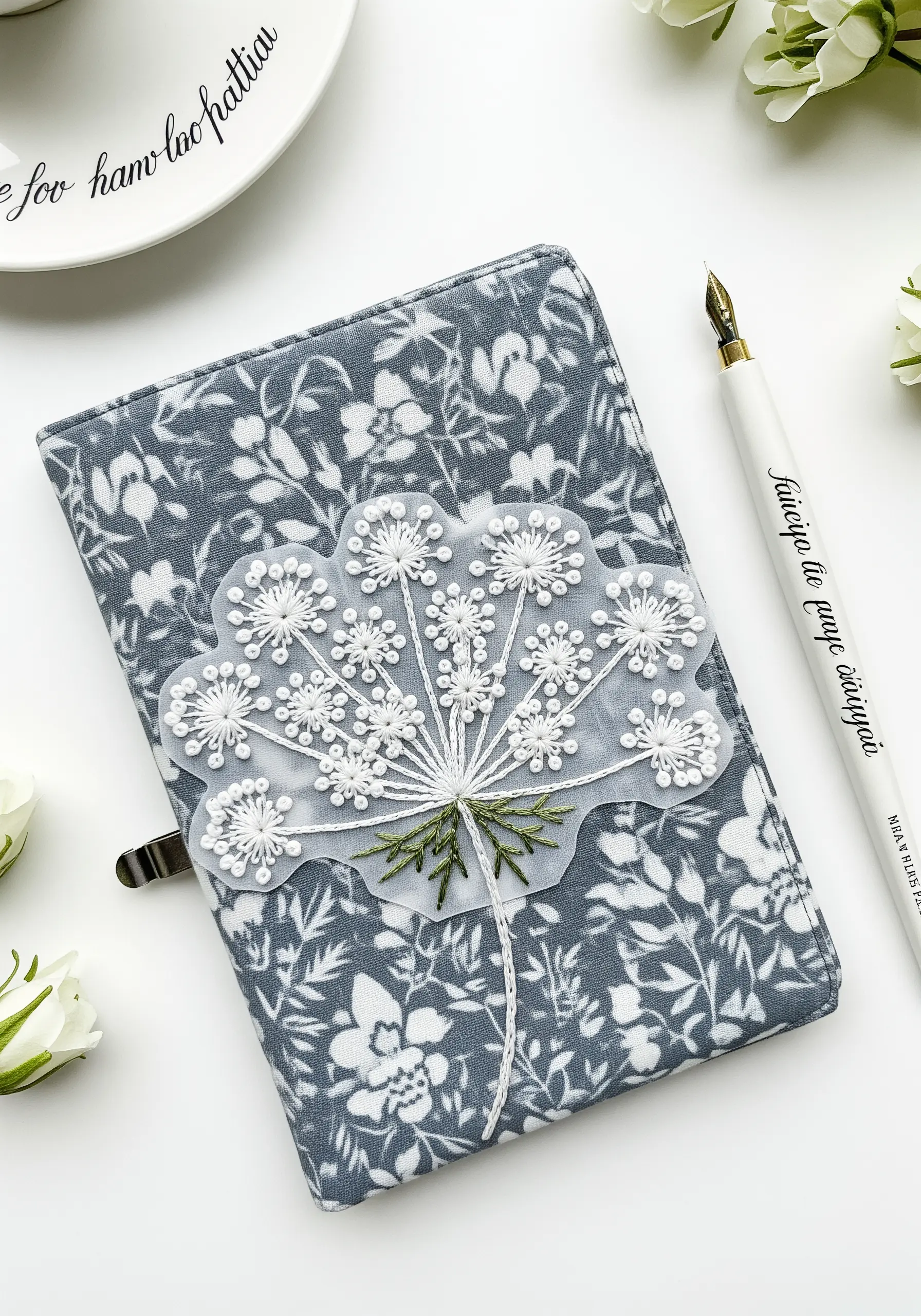 Embroidered Queen Anne's Lace on a sheer organza patch, placed over a floral-patterned journal.