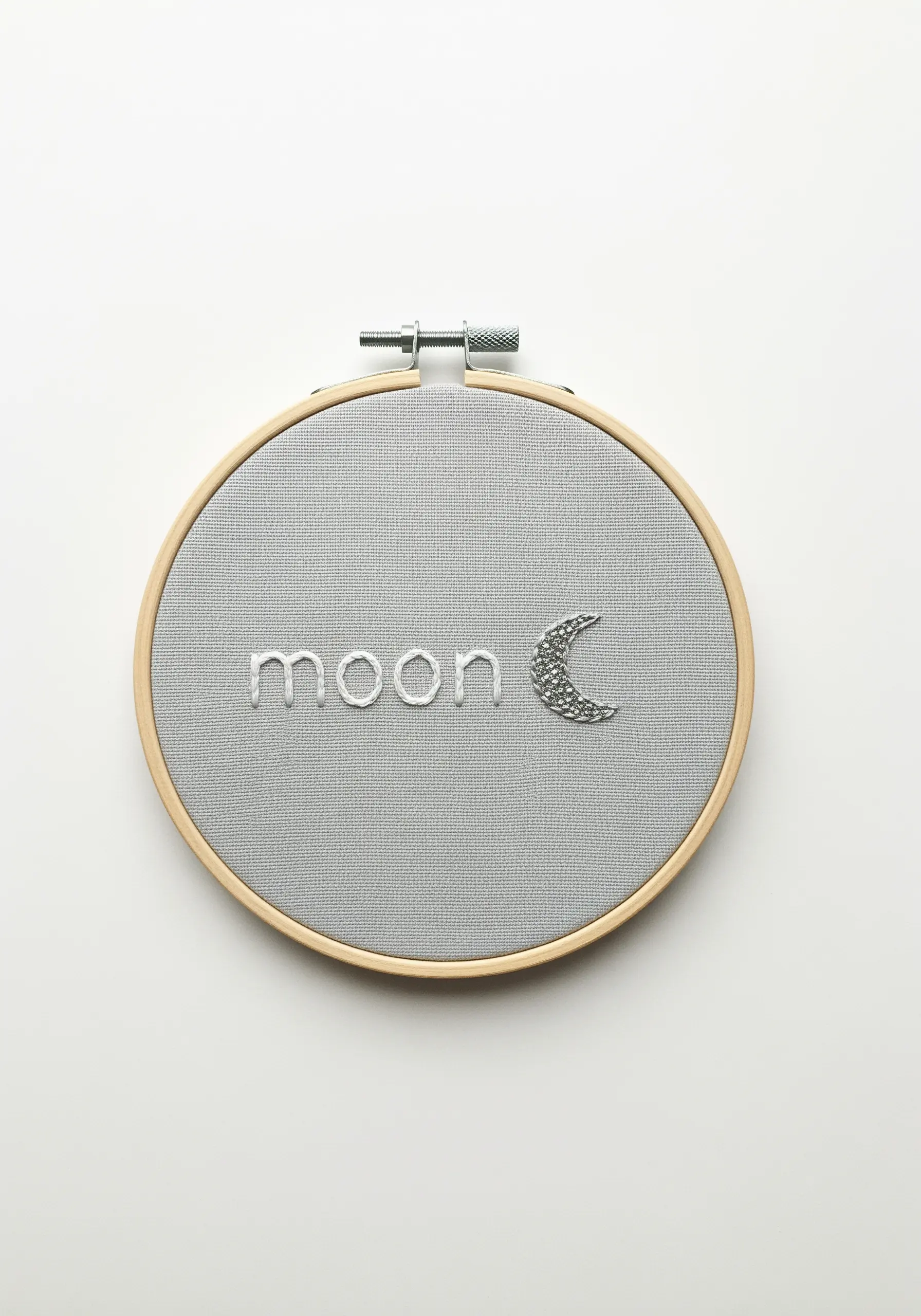 The word 'moon' embroidered in white, with the 'c' as a crescent of silver French knots.