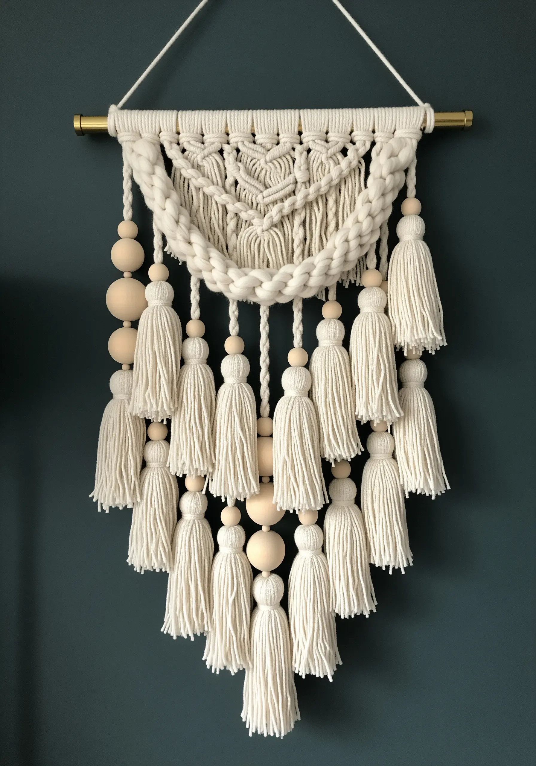 Macrame wall hanging with multiple rows of tassels and large, light-colored wooden beads.