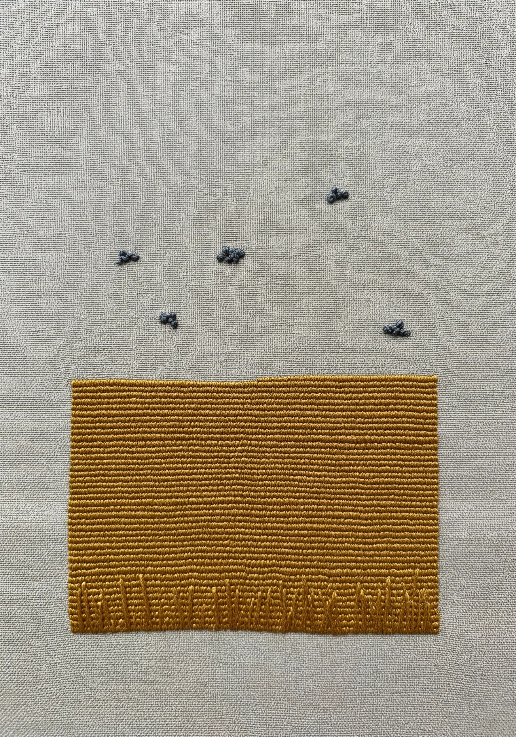 A block of yellow satin stitch with tiny grey birds embroidered in the space above.