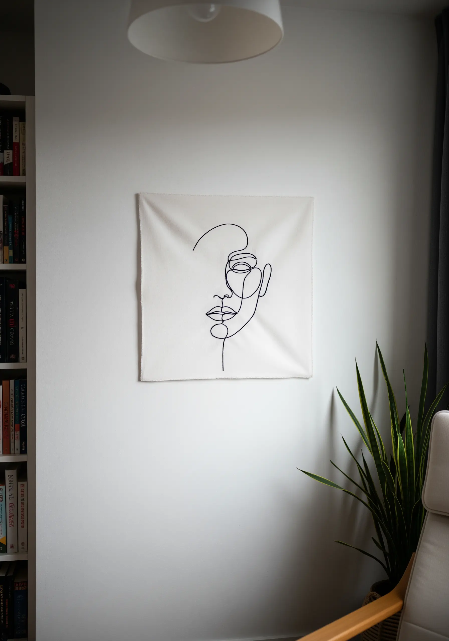 Minimalist single-line face profile embroidered in black thread on a white canvas.
