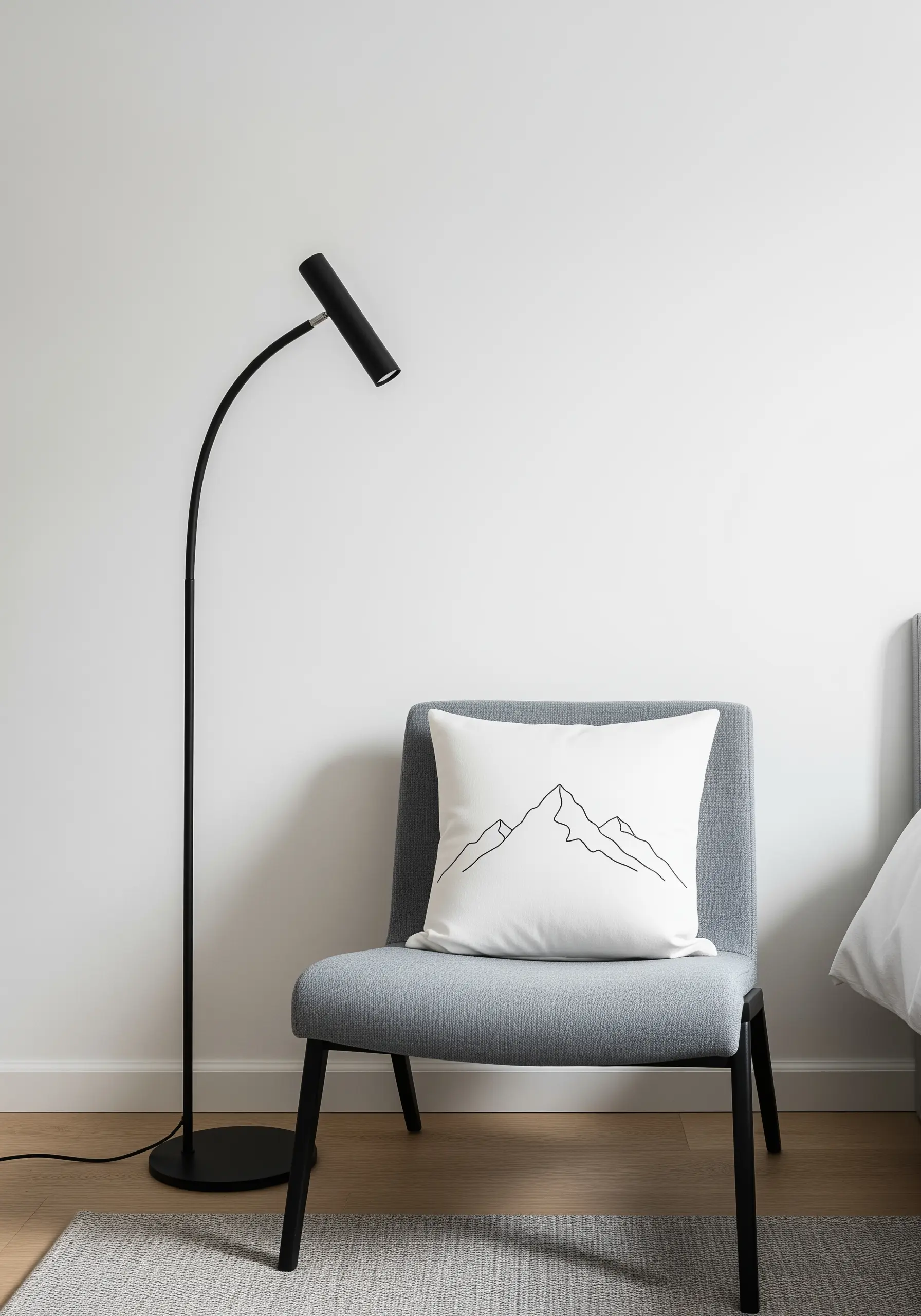 A minimalist line art drawing of a mountain range embroidered in black on a white pillow.