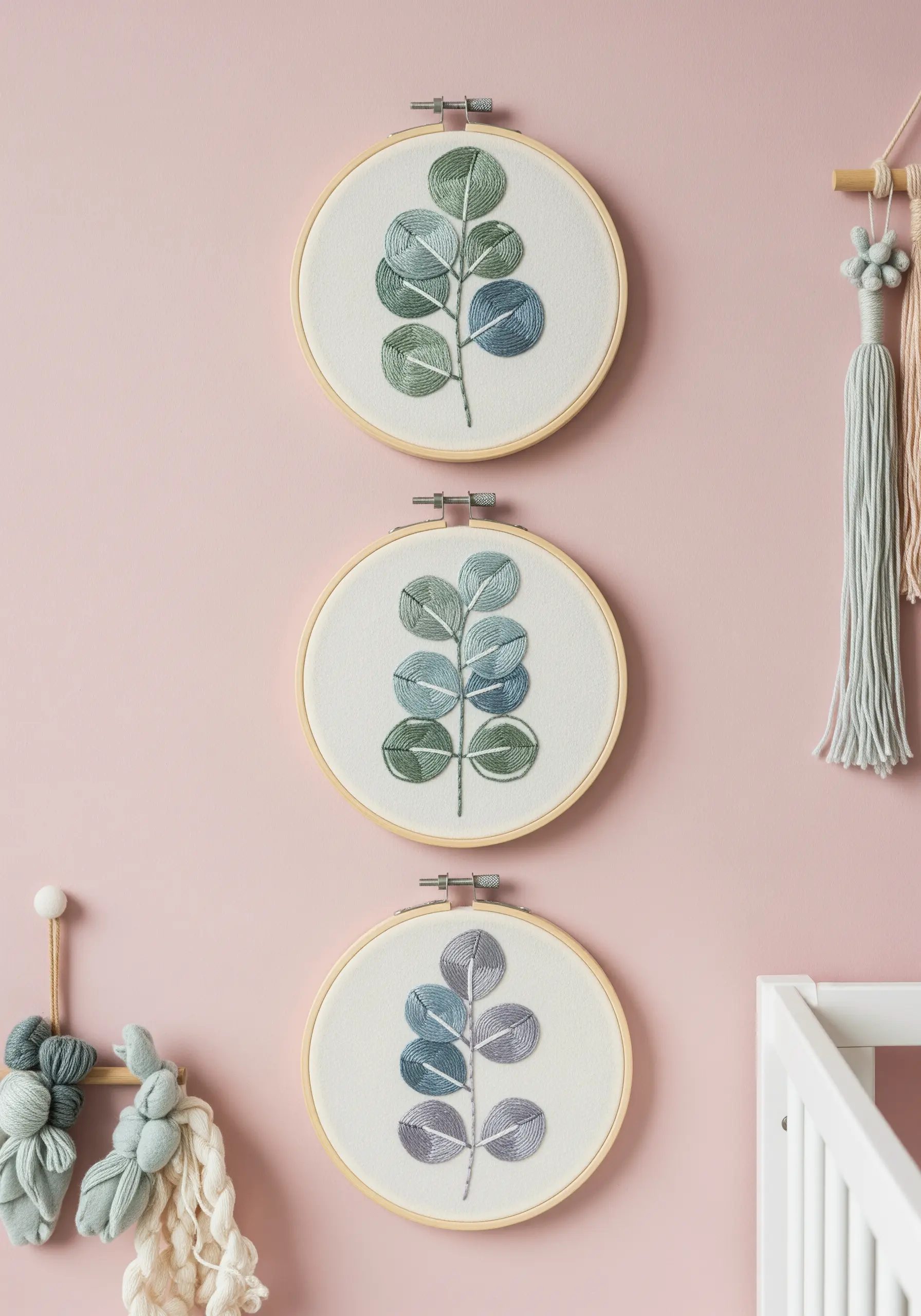 A triptych of embroidery hoops showing eucalyptus branches in muted greens, blues, and purples.