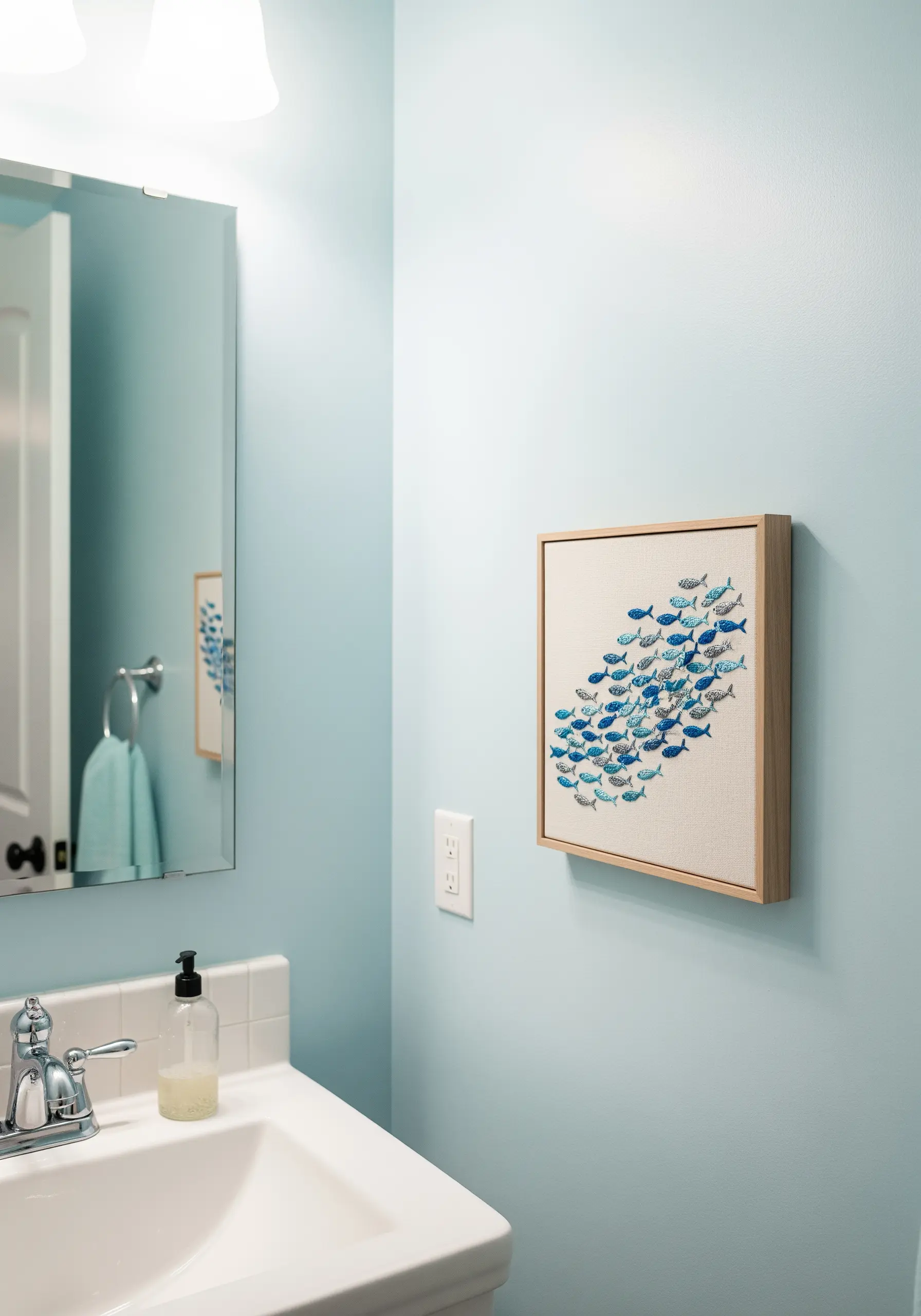 Framed embroidery of a school of fish swimming in a dynamic curve.