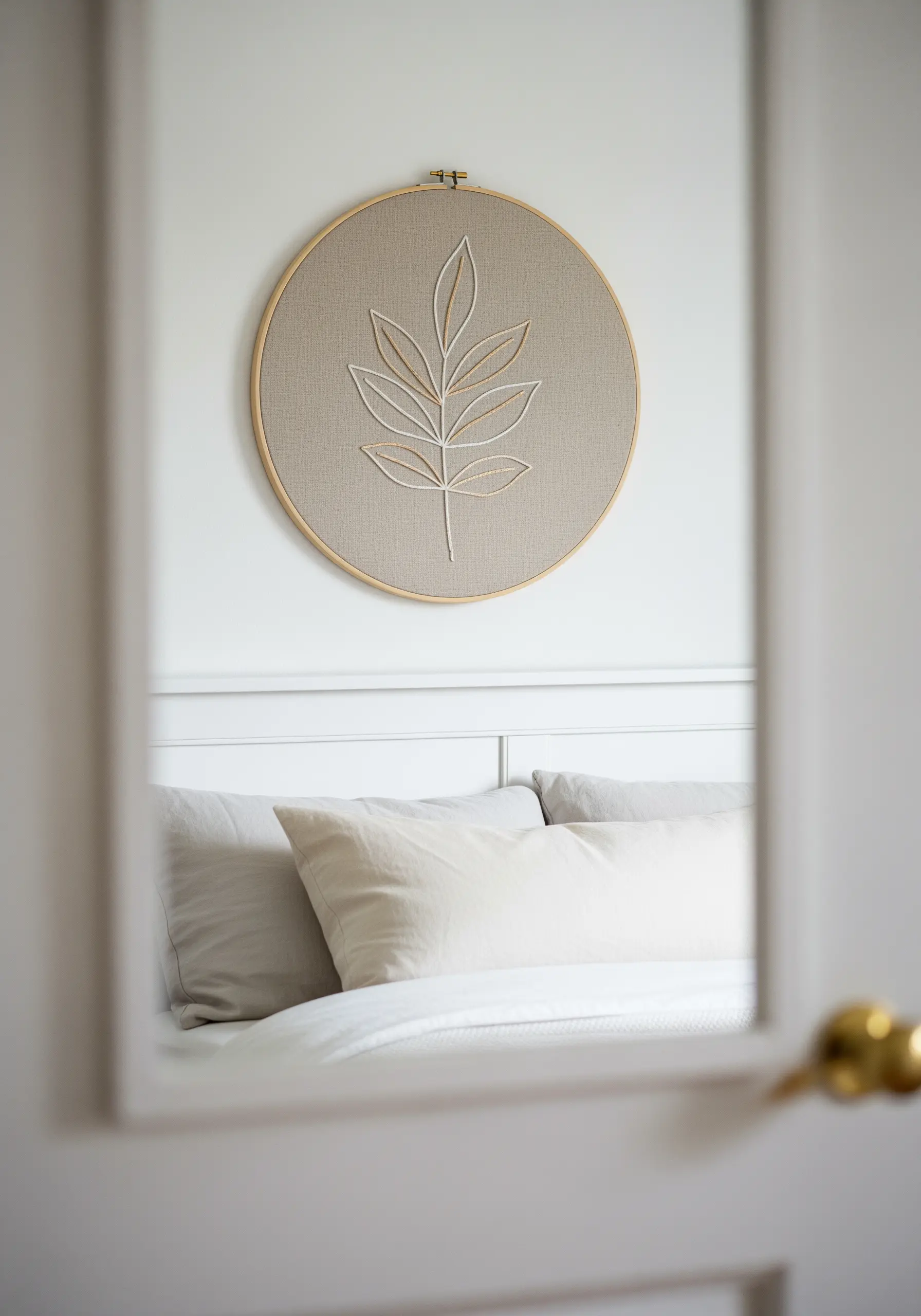 Minimalist hoop art of a leaf outline in two neutral, complementary thread colors.