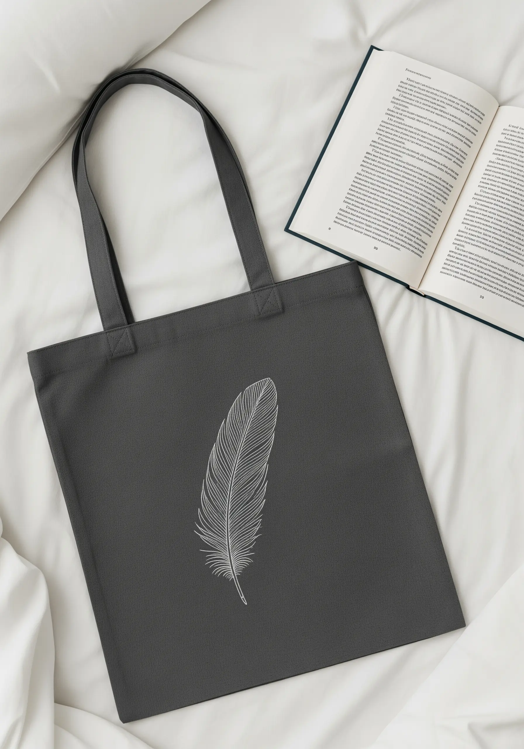 A single, delicate feather embroidered in fine white thread on a charcoal grey tote.