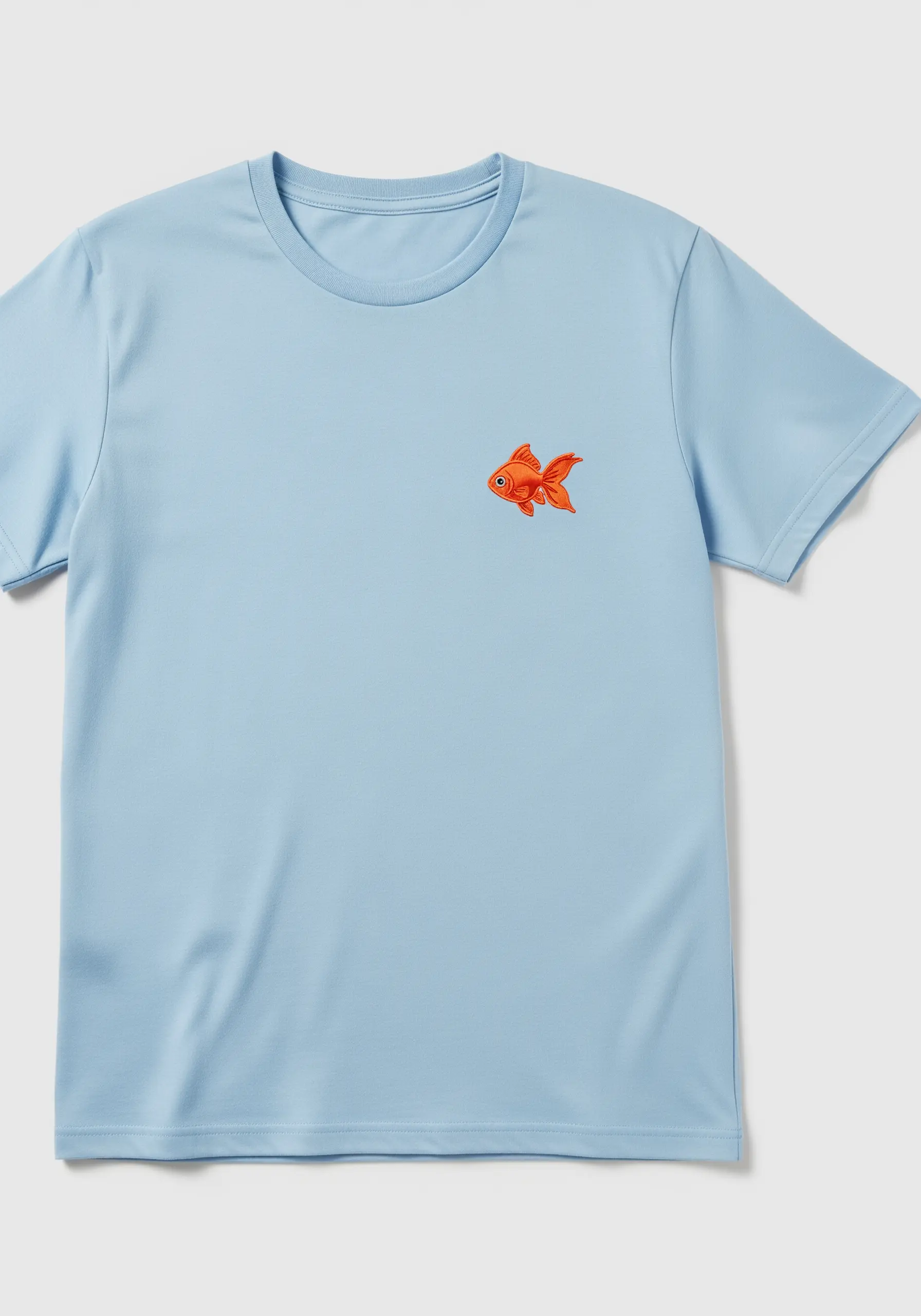 A small, vibrant orange embroidered goldfish on a light blue t-shirt.