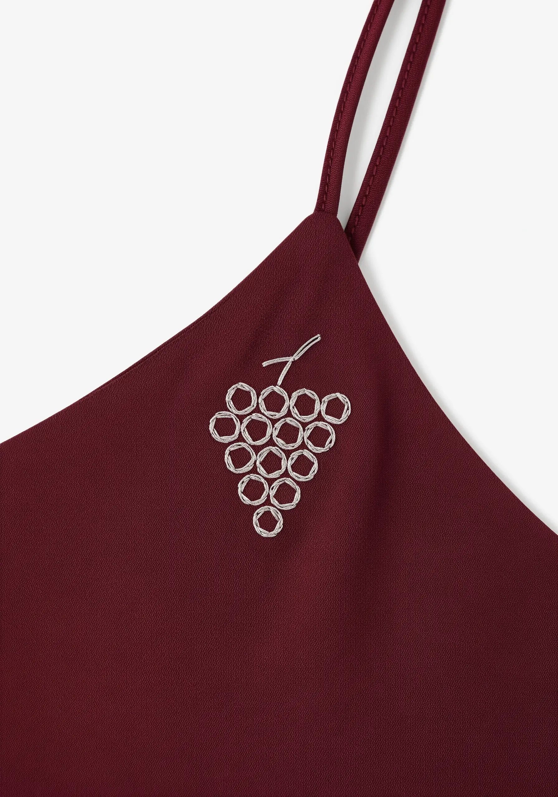 An abstract cluster of grapes embroidered in light thread on a burgundy camisole.