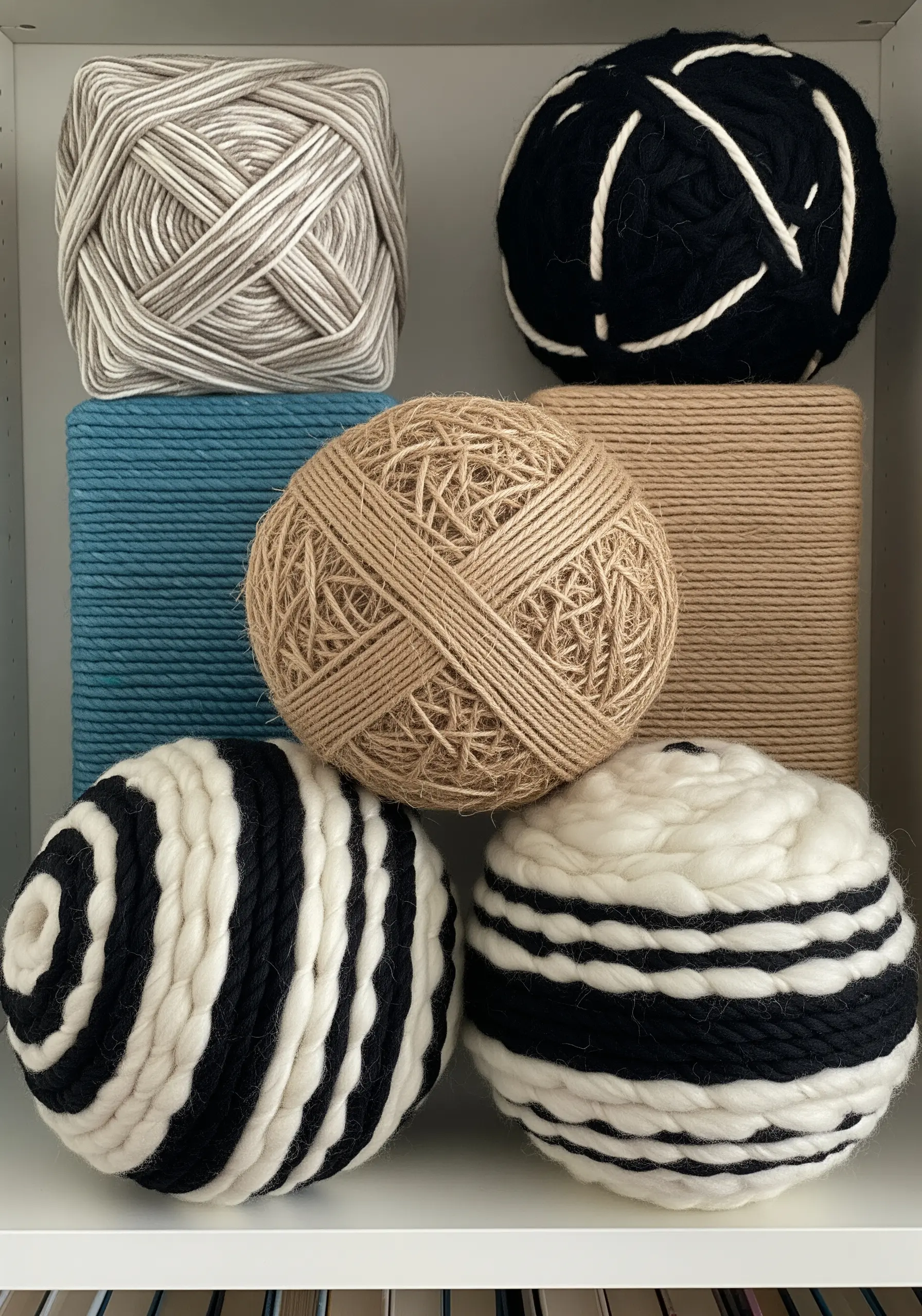 A collection of spheres and cubes wrapped in various colors and textures of yarn.