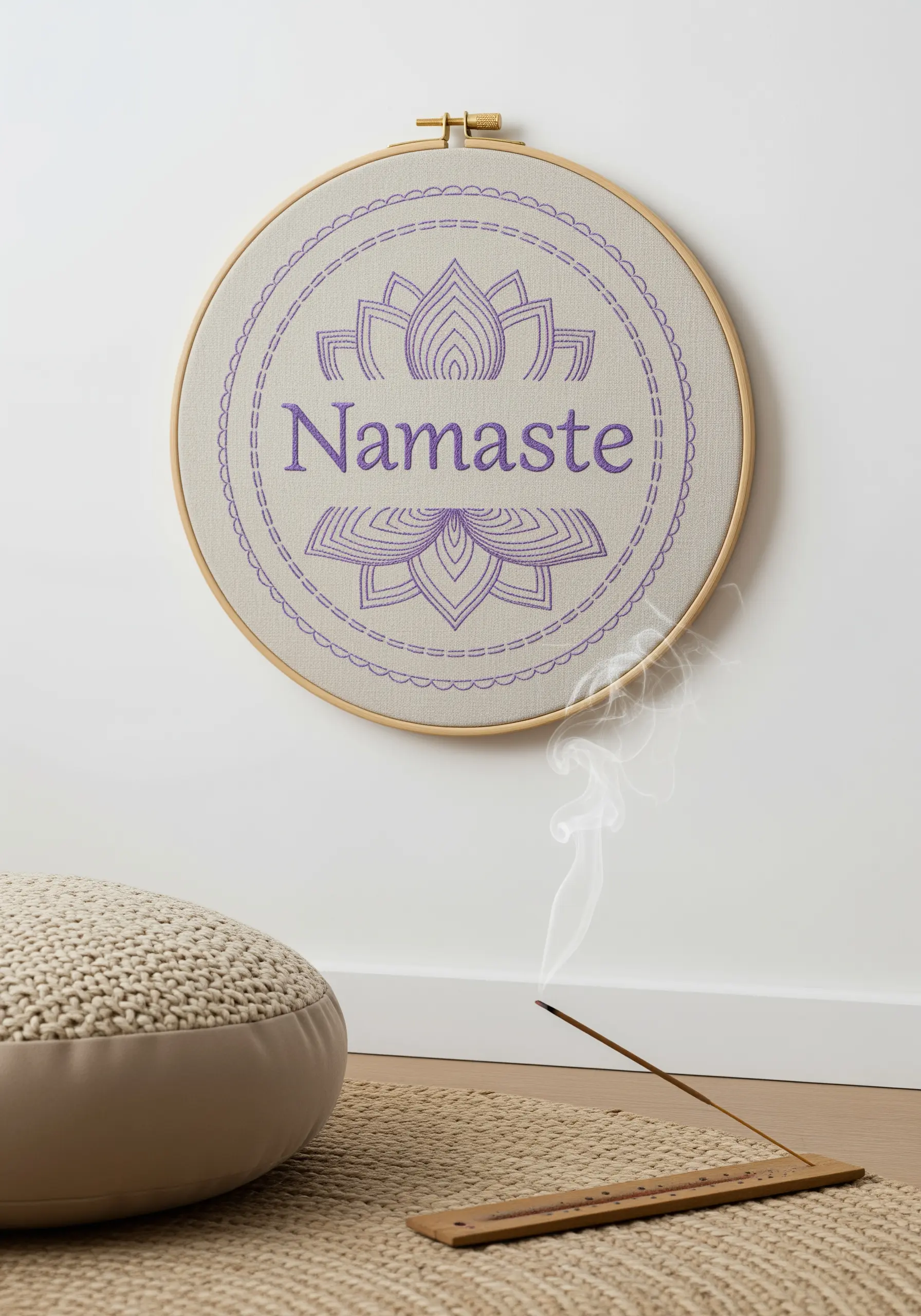 The word Namaste and a lotus flower stitched in purple thread inside an embroidery hoop.