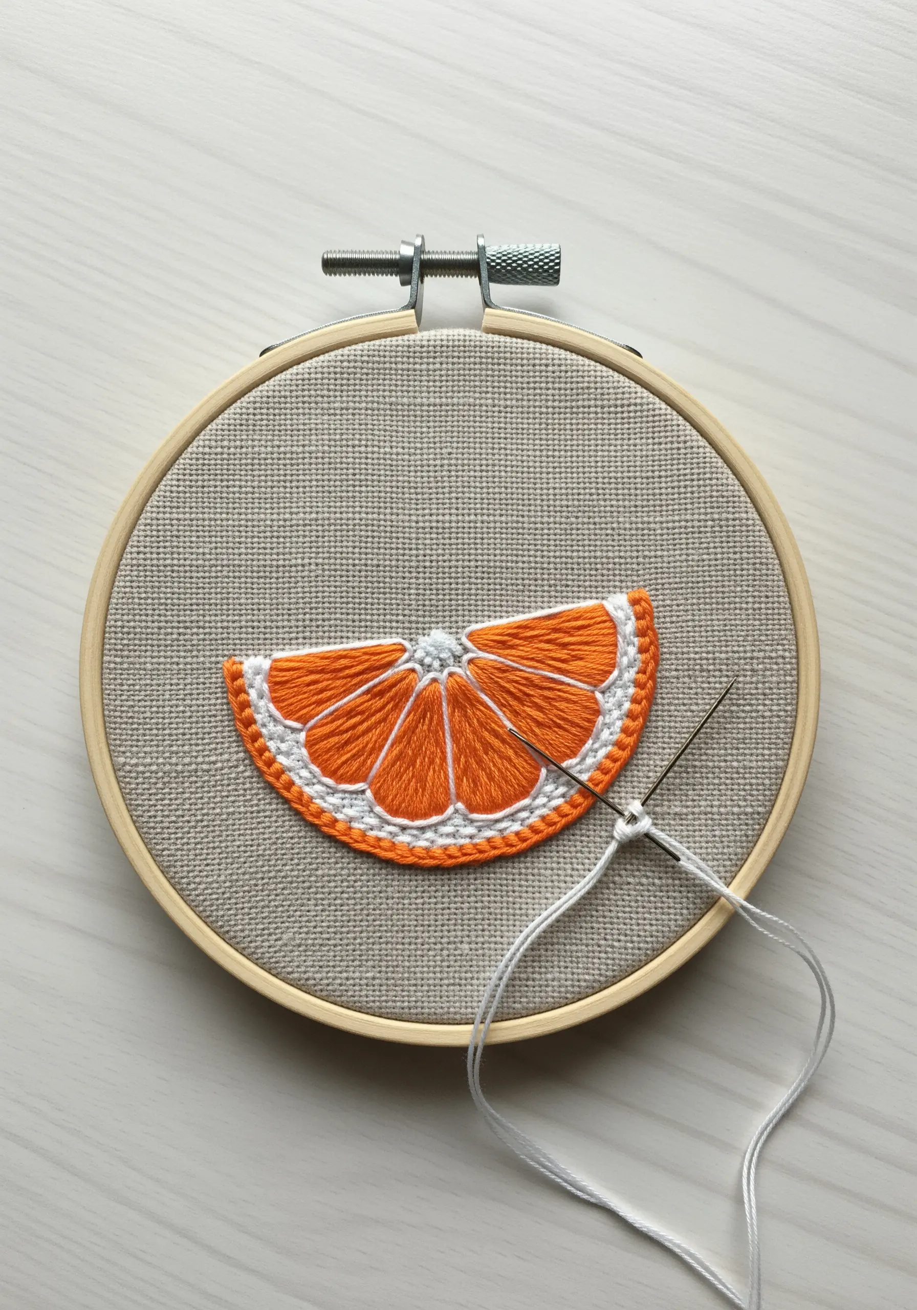 An embroidered orange slice with a thick, raised white outline defining the segments.