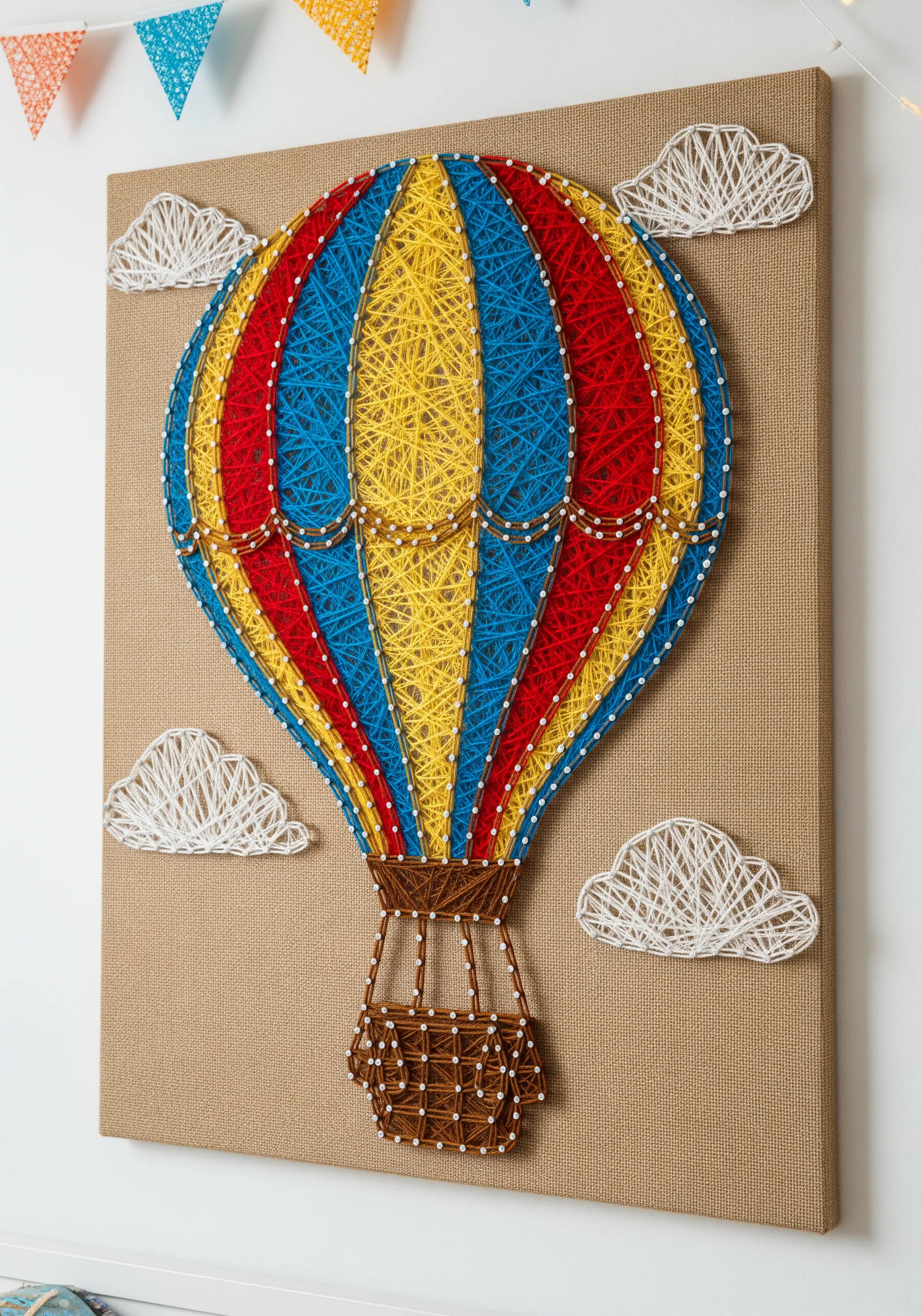 Colorful string art hot air balloon and clouds on a burlap canvas
